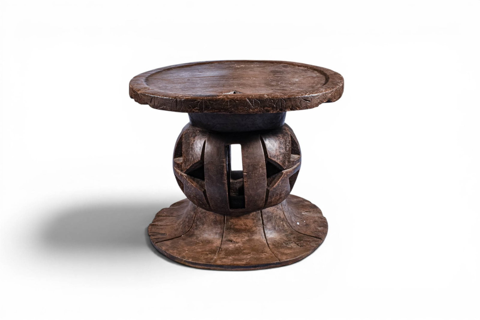 MANGBETU WOODEN STOOL: Ca. 19th century AD. >A finely carved wooden stool with a circular seat resting on a distinctive openwork support. The central section is formed as a hollowed, drum-like structure with vertical struts