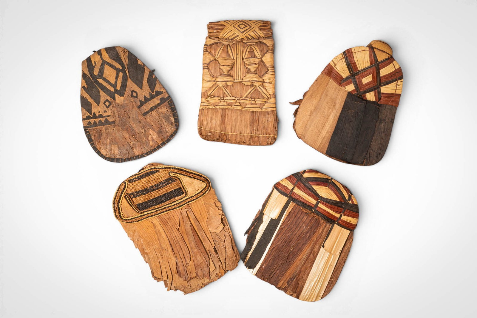 GROUP OF MANGBETU NEGBE: Ca. 20th century AD. >A group of five Mangbetu negbe, formed from bark and plant fibres and decorated with bold geometric patterns in contrasting dark and natural tones. The pieces vary in form, inclu