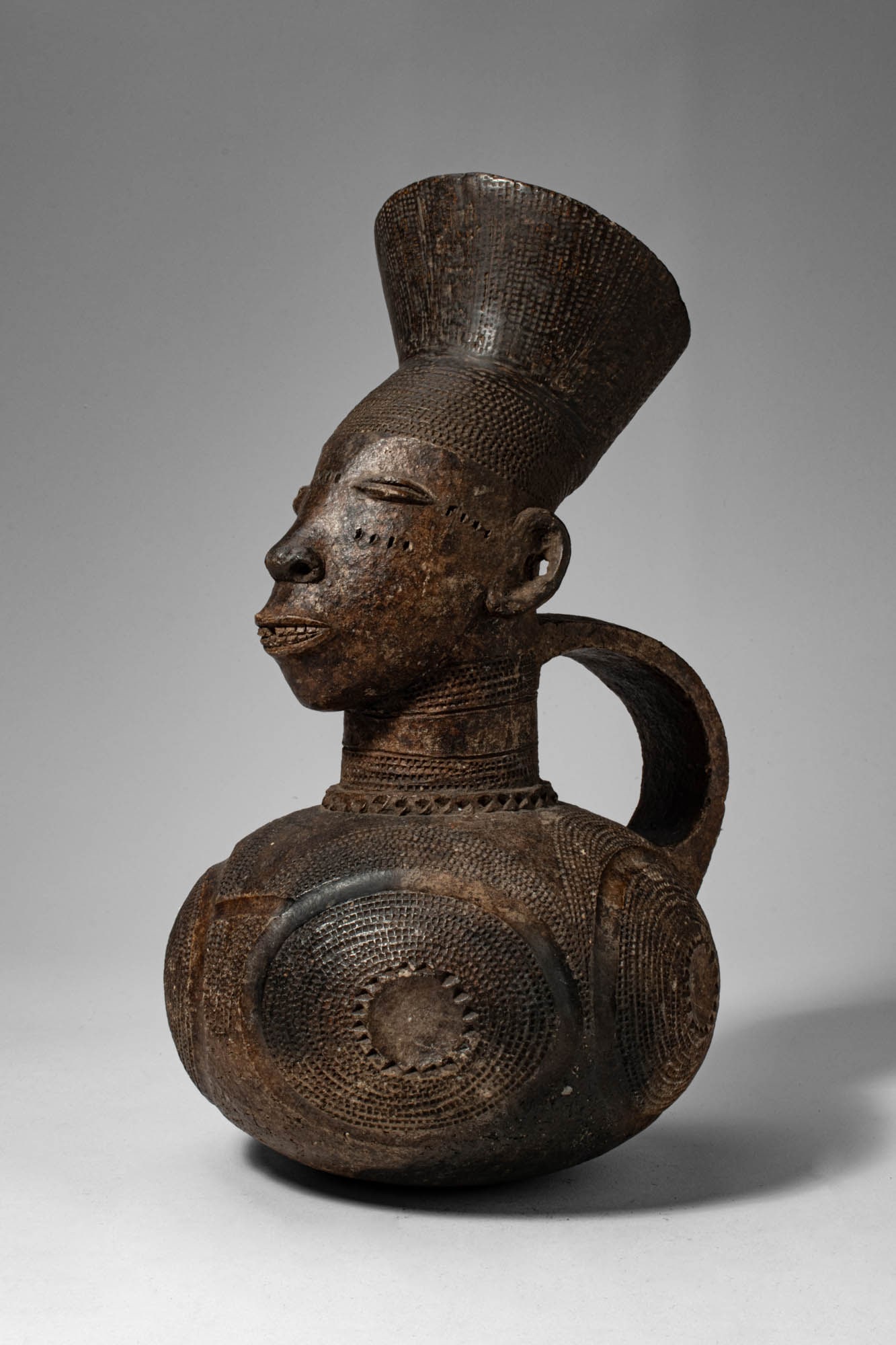 MANGBETU ANTHROPOMORPHIC TERRACOTTA VESSEL: Democratic Republic of the Congo, Ca. early 20th century AD. > A refined anthropomorphic terracotta vessel characteristic of Mangbetu artistic traditions, combining sculptural elegance with functional