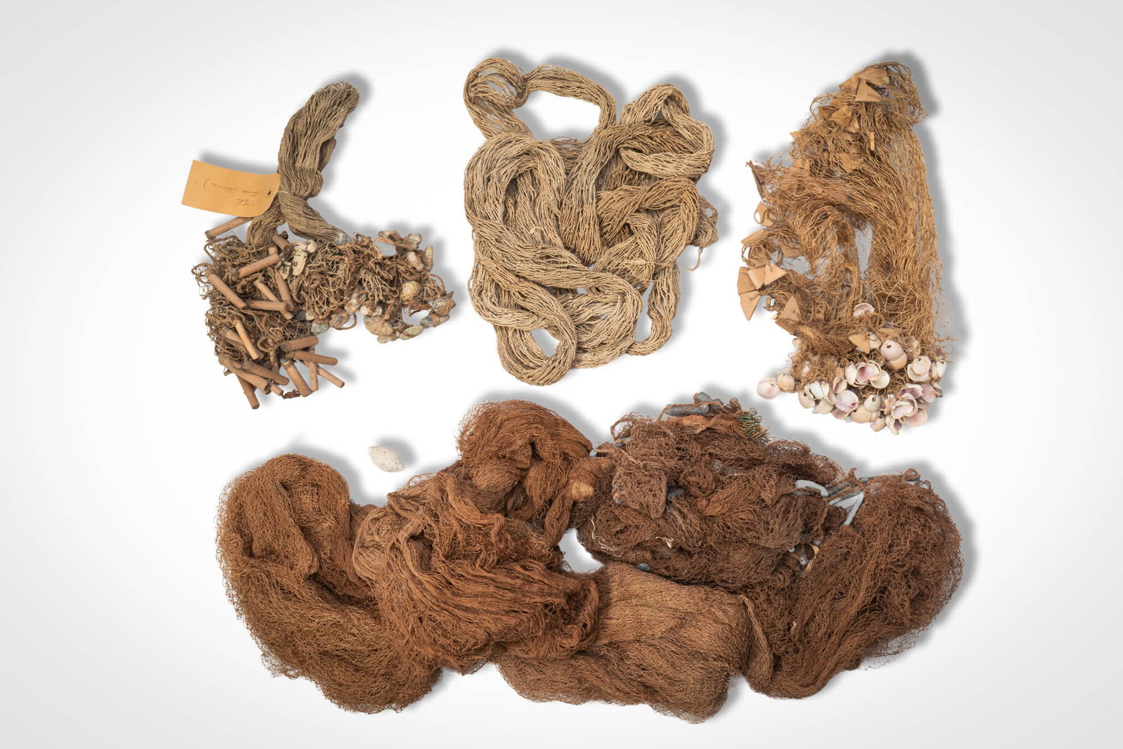 GROUP OF OCEANIC FISHING NETS: Ca. 19th - 20th century AD. >A selection of hand-made fishing nets and cordage, including bundles of knotted fibre netting, lengths of twisted line, and examples incorporating shell or organic element