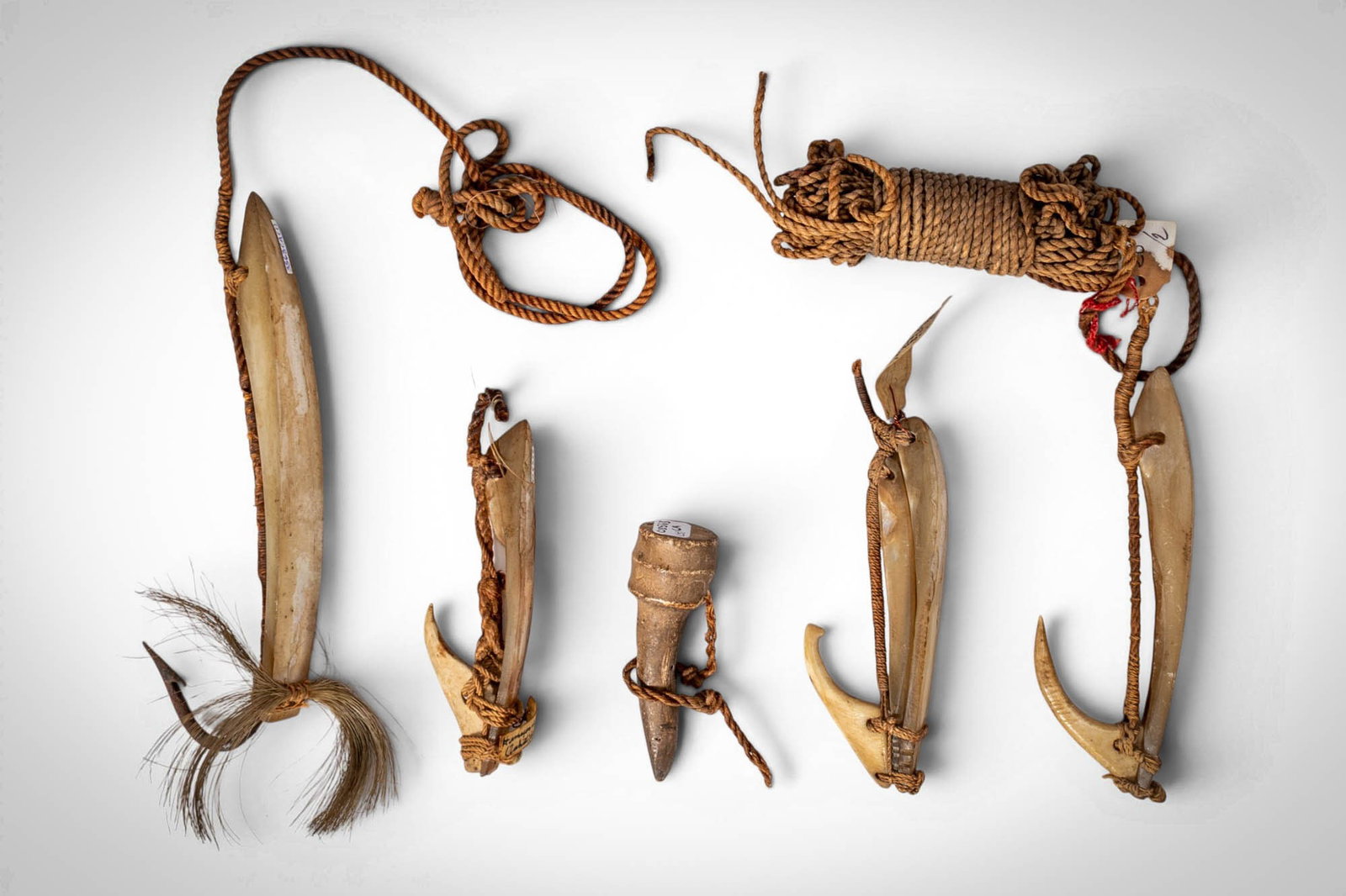 GROUP OF SOCIETY ISLANDS FISH HOOKS: Ca. late 19th - early 20th century AD. >A group comprising carved fish hooks of varying form, worked in bone or shell and wood, several retaining fibre bindings and lengths of cord. Including examples