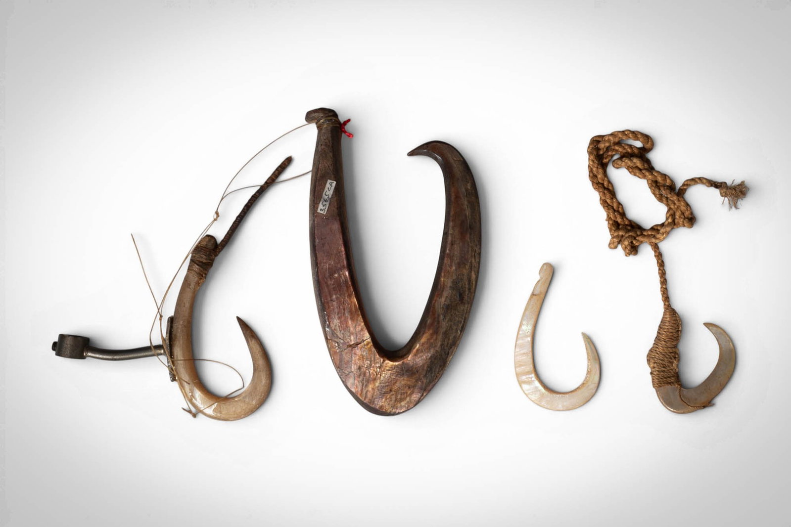 GROUP OF OCEANIC FISH HOOKS: Ca. late 19th - early 20th century AD. >A group comprising fish hooks in wood, shell, and bone, including large carved examples of pronounced curved form and smaller hooks of shell, some retaining fib