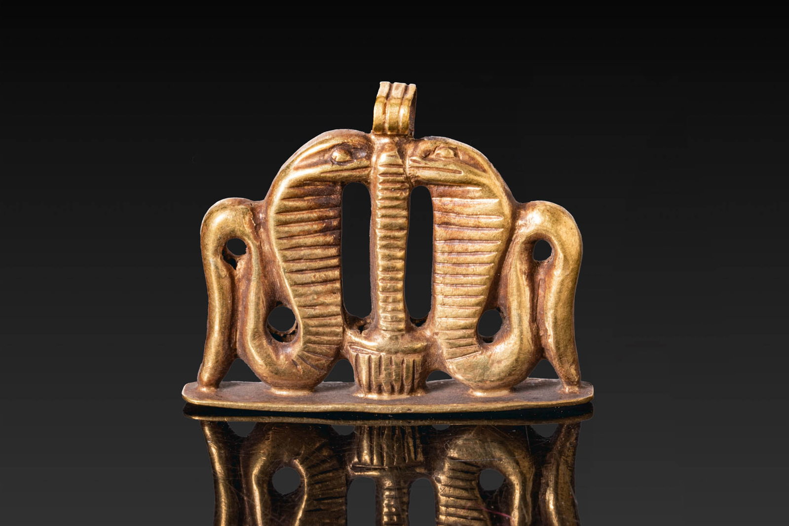 SUPERB EGYPTIAN GOLD PENDANT WITH COBRAS: Late Period, Ca. 664 - 332 BC. A rare openwork gold pendant with two confronted cobras flanking a central stem on a flat base, with a suspension loop above. For similar see: The British Museum, Museum