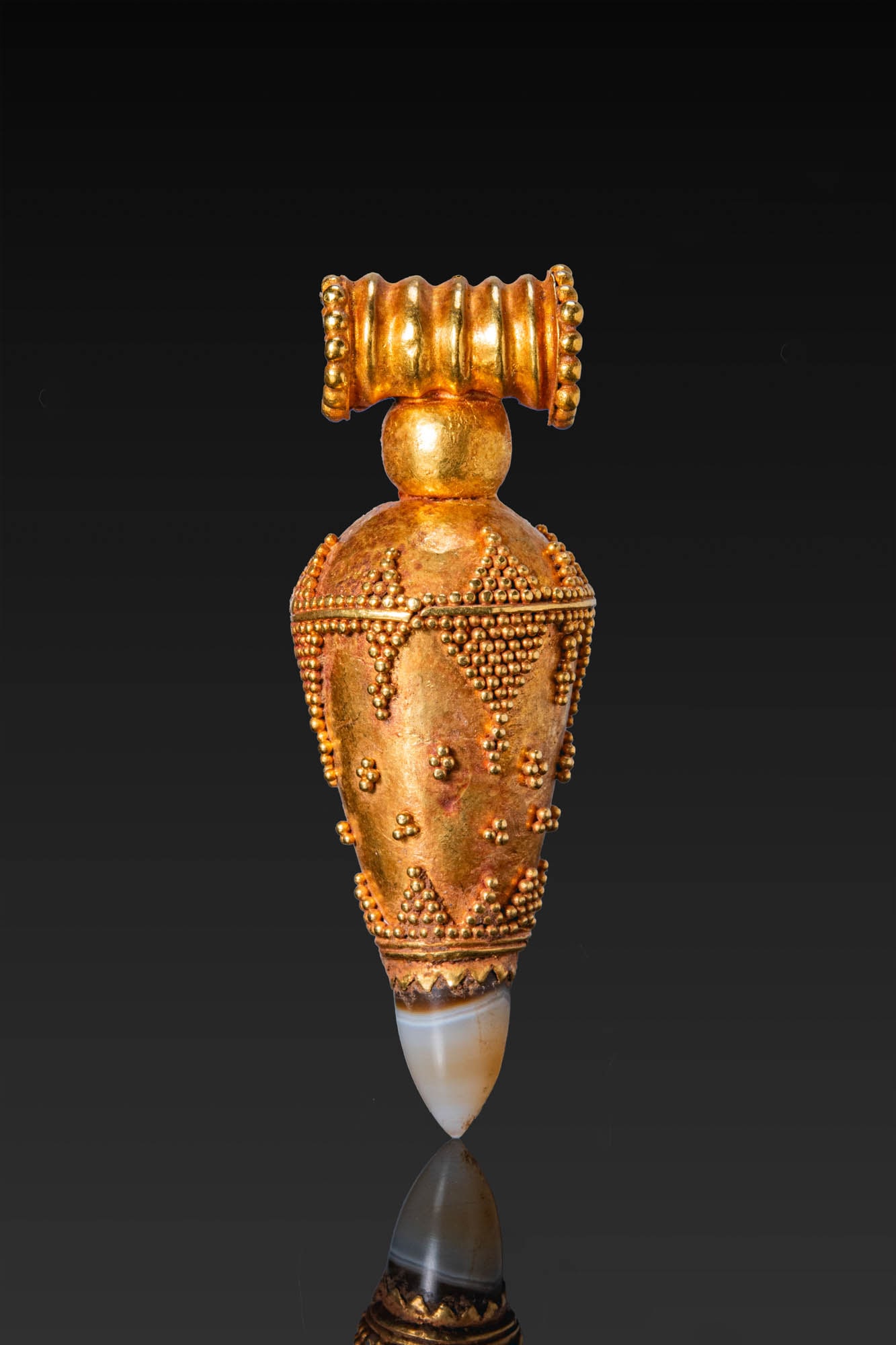 GRAECO-BACTRIAN GOLD GRANULATED PENDANT WITH AGATE: Ca. 300 - 100 BC. A gold pendant with a domed upper section above a conical body, decorated with wire bands and clusters of granulation. The lower end is set with a pointed agate terminal. The pendant