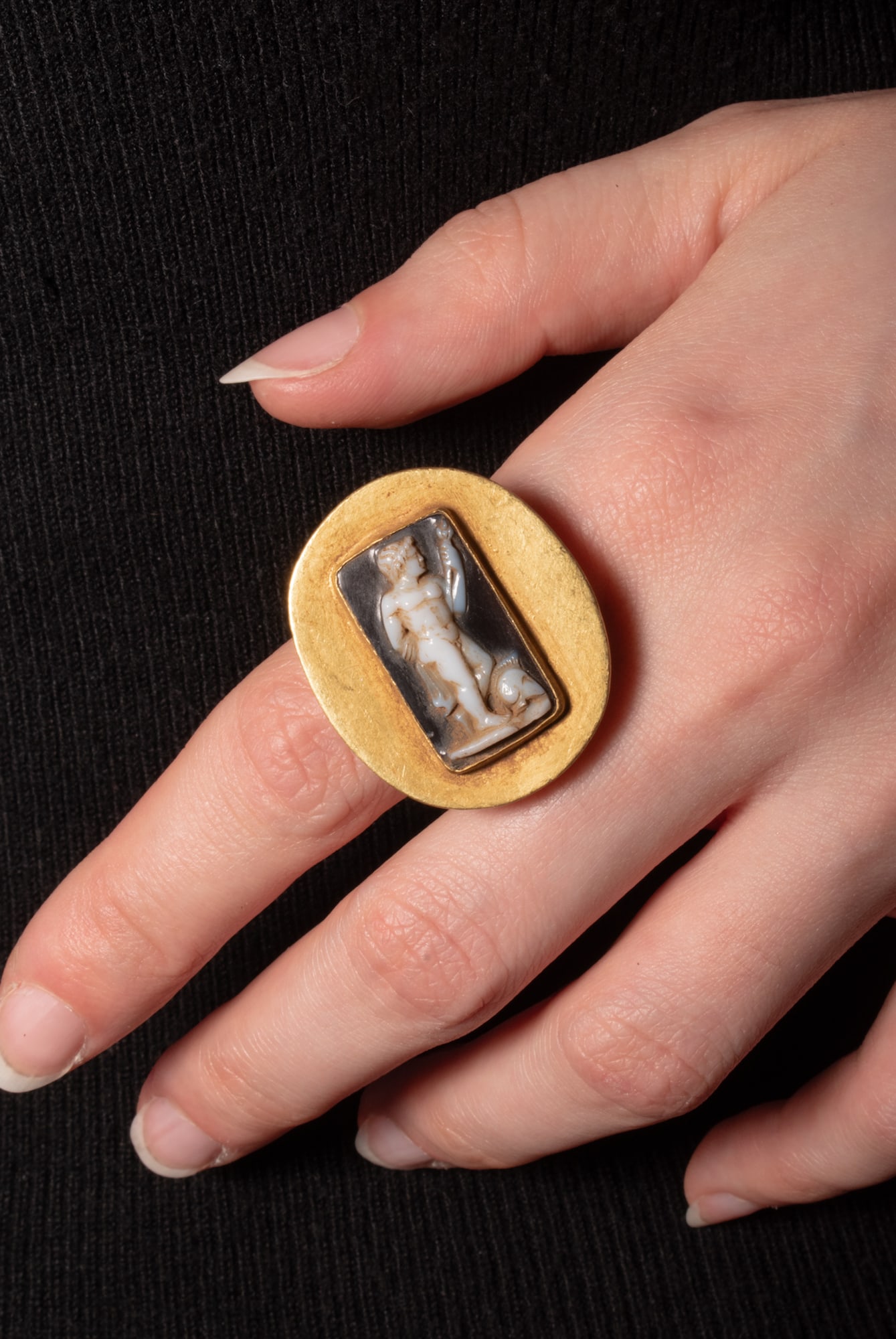 HEAVY ROMAN GOLD RING WITH CAMEO OF MARS WEARING A CORINTHIAN HELMET: Ca. 100 - 27 BC. A gold ring with a broad, rounded hoop and an oval bezel plate set with a rectangular cell containing a cameo carved with Mars standing nude, with a Corinthian helmet at his feet. For