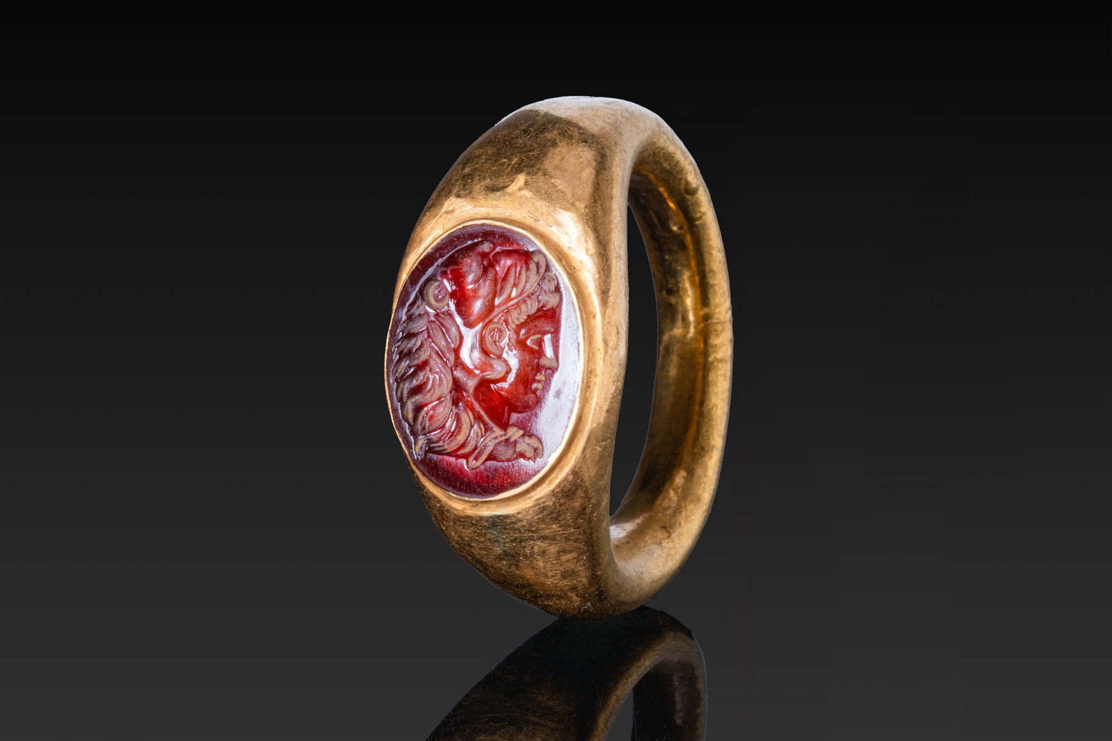 RARE ROMAN REPUBLICAN CARNELIAN INTAGLIO OF ALEXANDER THE GREAT IN GOLD RING: Ca. 200 - 27 BC. A carnelian intaglio engraved with the right profile portrait of Alexander the Great in the guise of Herakles, wearing the lion's skin headdress with the jaws drawn over his head and 
