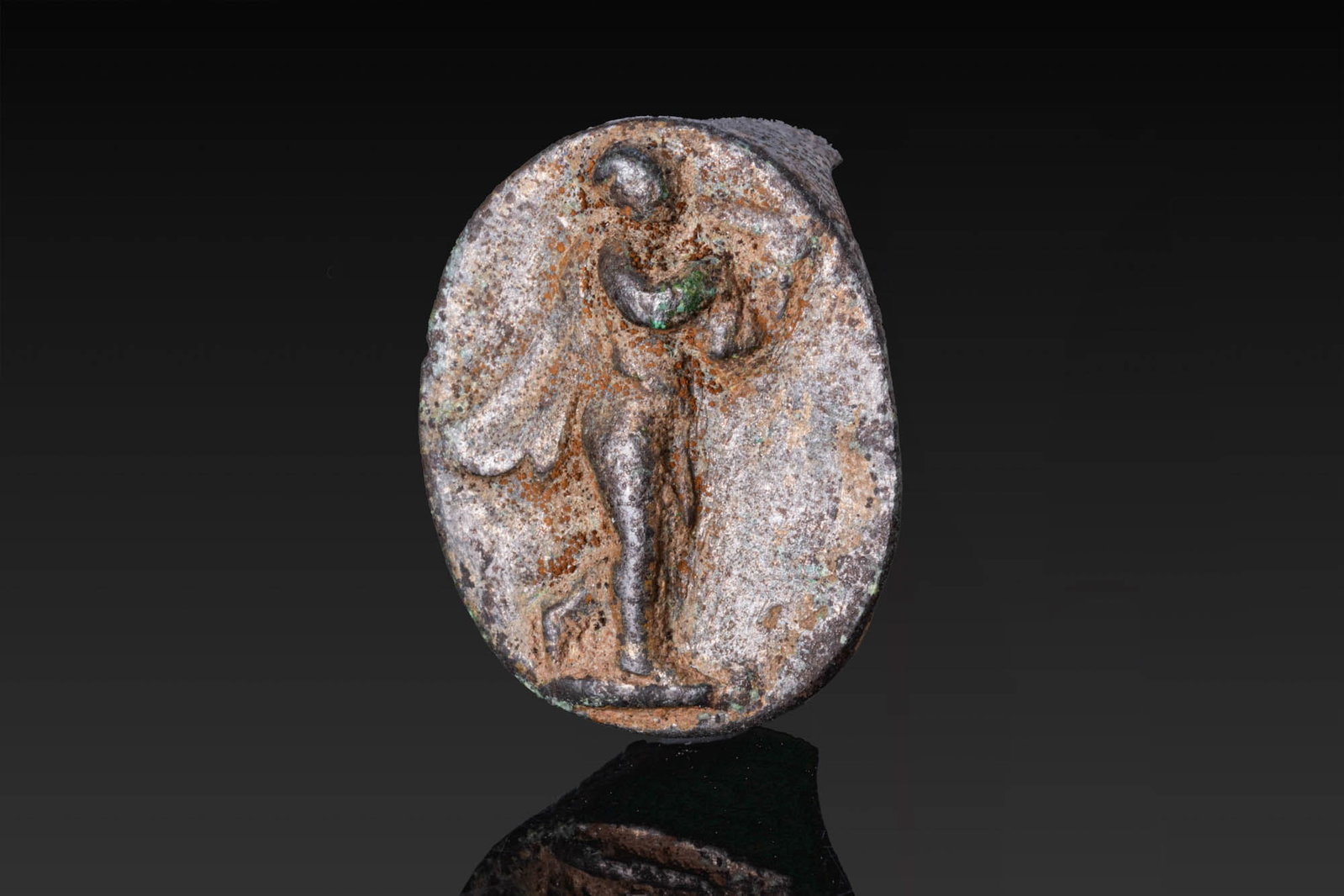 ROMAN SILVER RING BEZEL WITH APOLLO CITHAROEDUS: Ca. AD 1 - 300. A silver ring bezel engraved with Apollo Citharoedus standing in profile, with drapery falling from the shoulders. Size: 23mm x 19mm; Weight: 7.8g Provenance: Private London