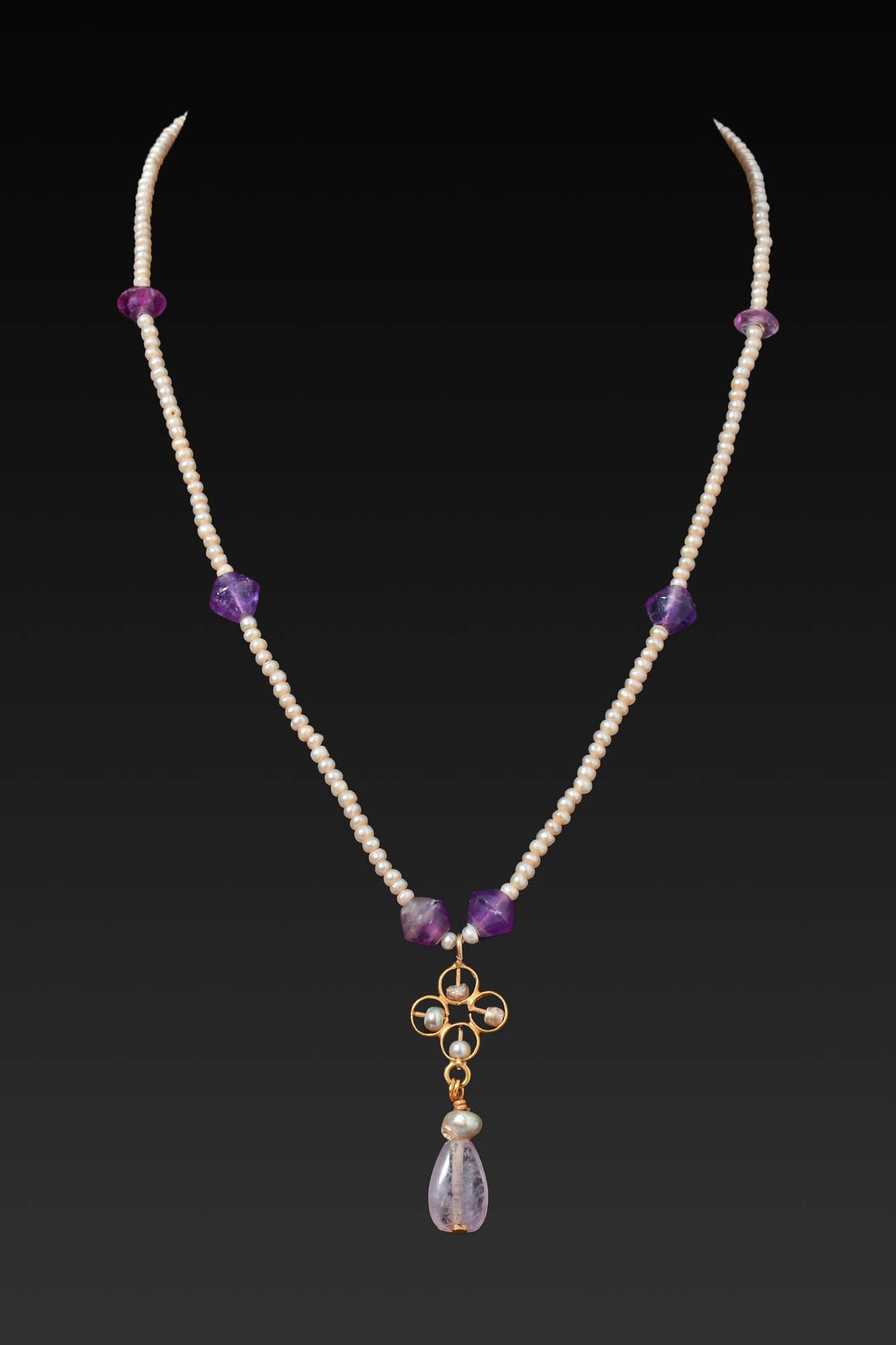 STUNNING BYZANTINE GOLD, PEARL AND AMETHYST NECKLACE: Ca. AD 500 - 700. A necklace with a strand of seed pearls interspersed with faceted amethyst beads, centred by an openwork gold pendant formed of four conjoined circles set with pearls and suspending 