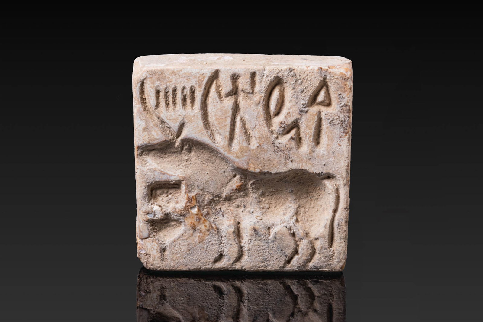 INDUS VALLEY WHITE STONE STAMP SEAL WITH BISON - ORIGINAL LAMBERT REPORT: Ca. 3000 BC. A white stone stamp seal, nearly square in form, with a pierced handle on the reverse. The face shows a standing “bison” with its head raised, with cultic utensils or symbols bene