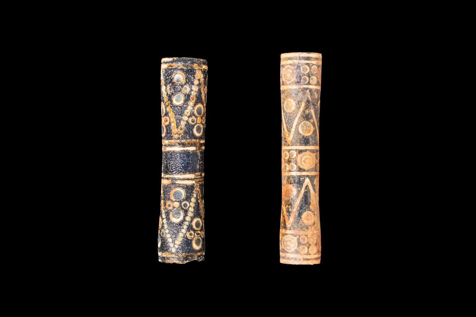 PAIR OF CHINESE WARRING STATES GLASS CYLINDRICAL BEADS: Ca. 475 - 221 BC. A pair of dark blue glass cylindrical beads, each pierced lengthwise and decorated with four white double bands, one near each end and two in the central area. The double bands divid