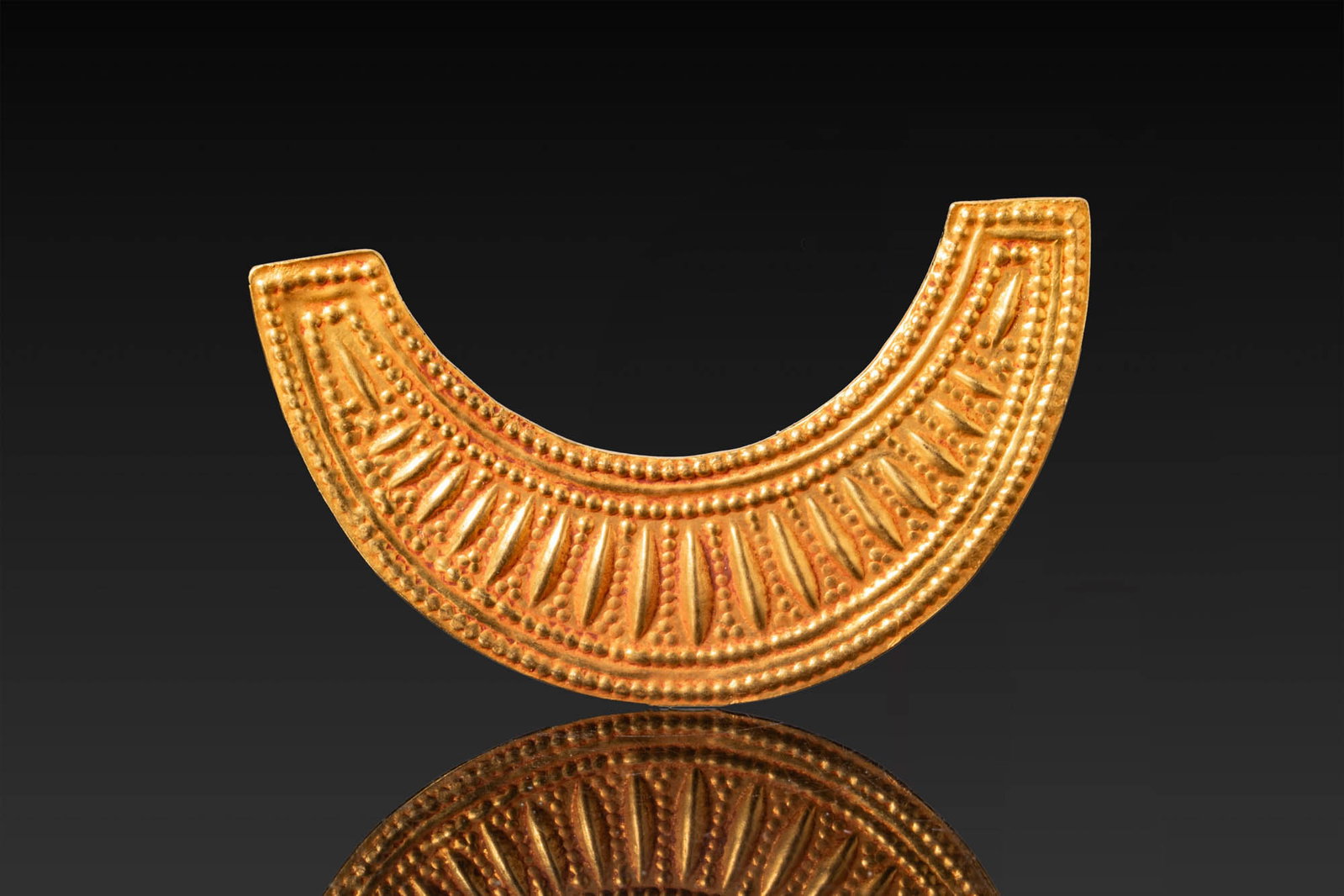 EGYPTIAN GOLD BROAD COLLAR AMULET: Late Period, Ca. 664 - 332 BC. A gold broad collar amulet with squared terminals. The obverse is decorated in repousse with concentric beaded borders enclosing a band of radiating leaf-shaped motifs. 