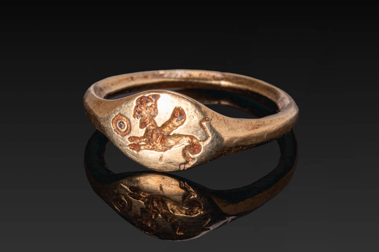 GREEK GOLD RING WITH SPHINX AND SUN DISC: Ca. 400 - 300 BC. A gold ring with a slender hoop widening to an oval bezel engraved with a recumbent sphinx in profile, with a sun disc before it. For similar see: The Classical Art Research Centre, 