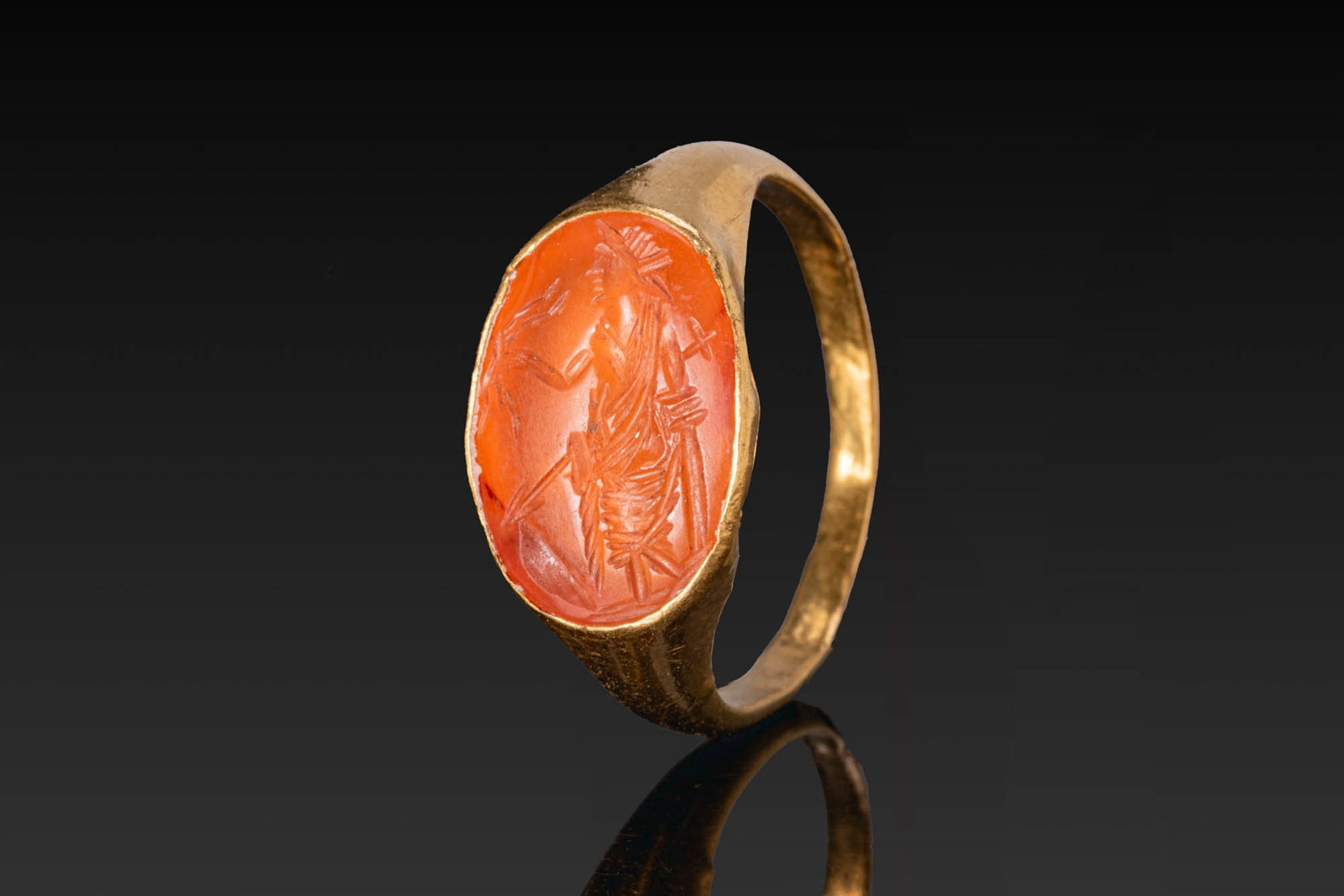 ROMAN GOLD RING WITH CARNELIAN INTAGLIO OF MARS: Ca. AD 200. A gold ring with a tapering hoop and an oval bezel set with a carnelian intaglio engraved with Mars standing, with a spear and shield beside him. For similar see: The Classical Art Researc