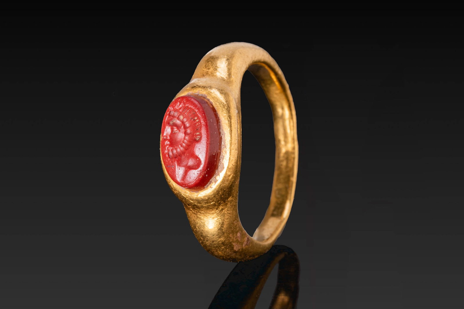 ROMAN GOLD RING WITH RED JASPER INTAGLIO OF AN EMPEROR: Ca. AD 1 - 300. A gold ring with a tapering hoop and an oval bezel set with a red jasper intaglio engraved with the profile bust of an emperor. For similar see: The Classical Art Research Centre, Reco