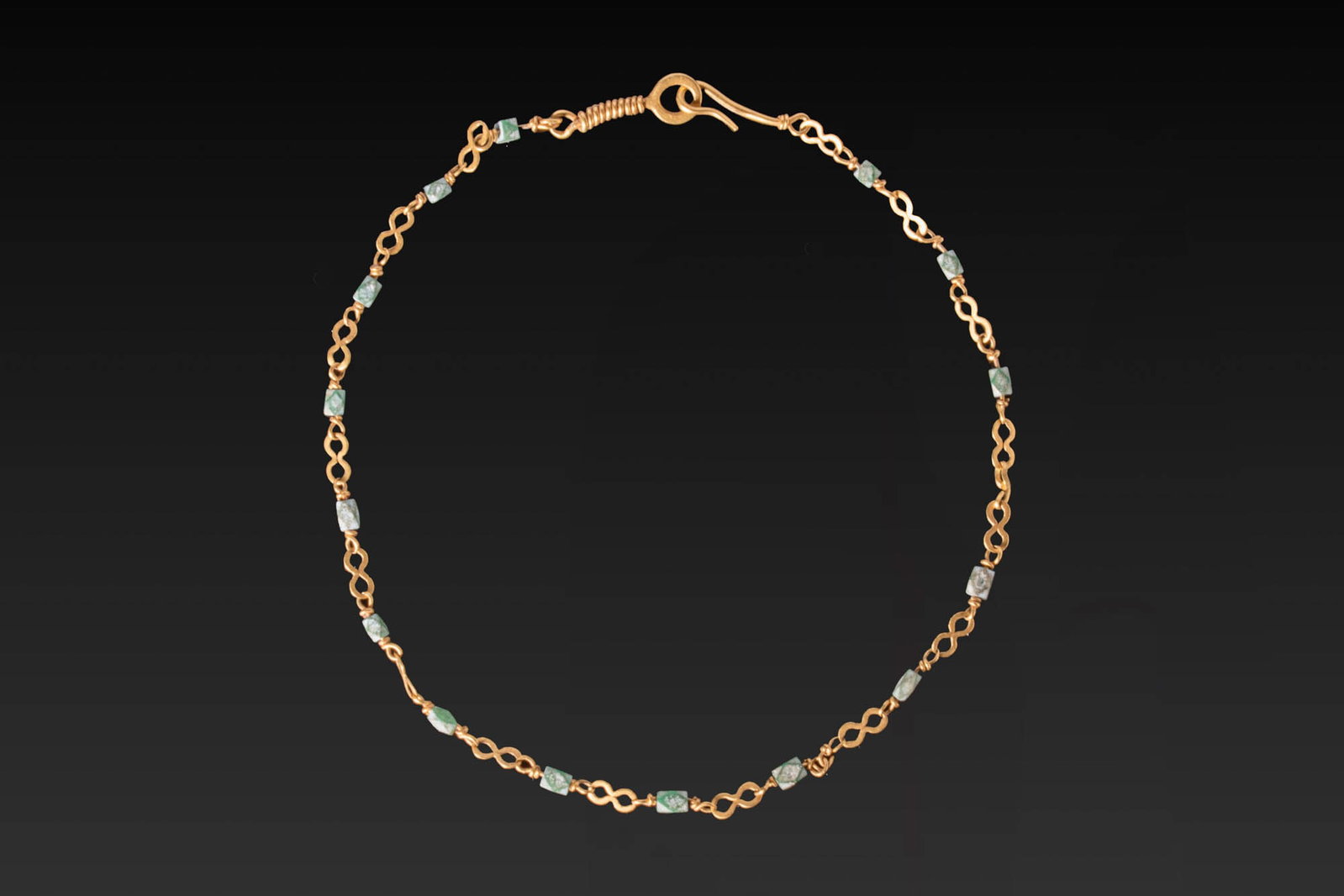 ROMAN GOLD NECKLACE WITH EMERALDS: Ca. AD 1 - 300. A gold necklace composed of alternating double-loop links and faceted emerald beads. The chain is finished with a hook-and-eye clasp with a wire-wrapped terminal. For similar see: The 