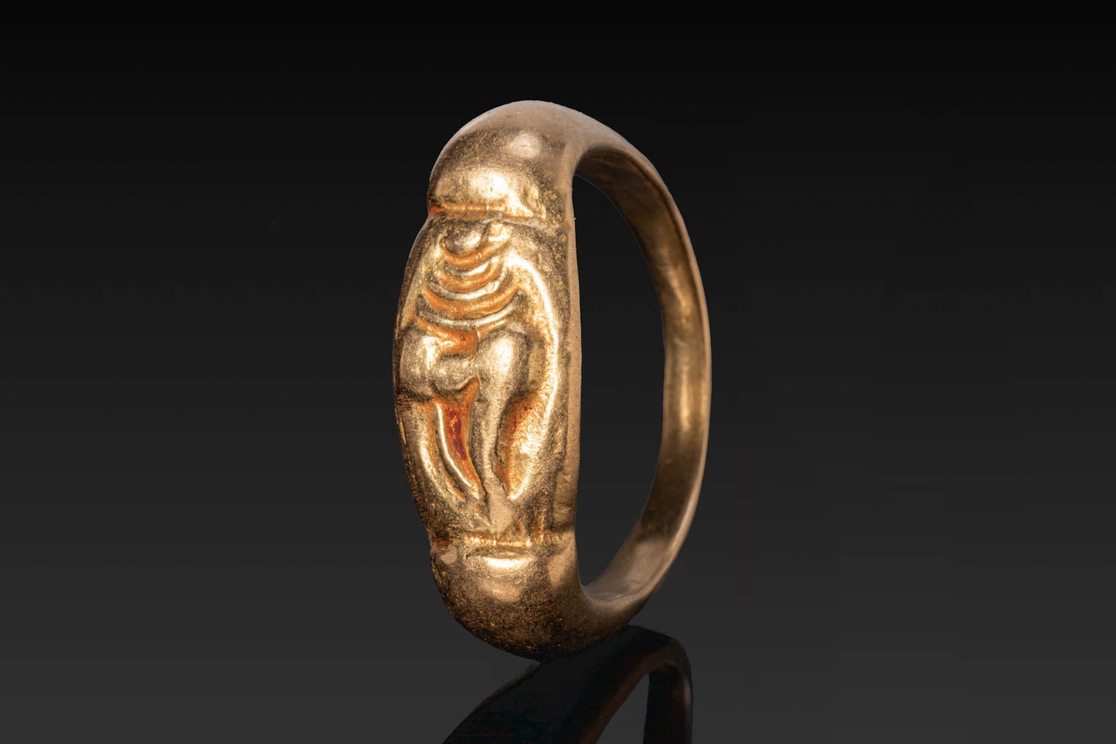 MEDIEVAL JAVANESE SOLID GOLD RING: Ca. AD 700 - 1000. A solid gold ring with a rounded hoop expanding to an elongated bezel with a stylised motif in low relief. Size: D:17.12mm / US: 6 3/4 / UK: N; Weight: 7.7g Provenance: From a priva