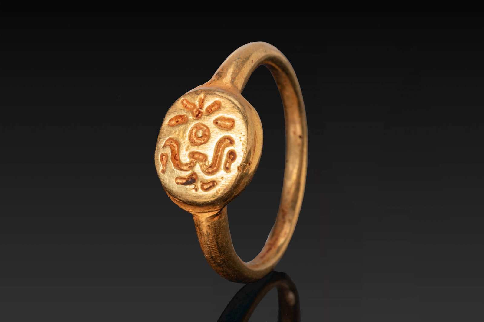 MEDIEVAL SOLID GOLD RING: Ca. AD 700 - 1000. A gold ring with a slender hoop expanding to an oval bezel with incised motifs. Size: D:15.9mm / US: 5 1/4 / UK: K; Weight: 4.6g Provenance: From a private London collection; earlie