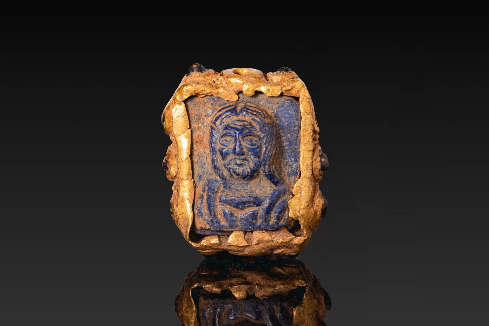 RARE BYZANTINE GOLD AND LAPIS LAZULI PENDANT WITH CHRIST AND VIRGIN MARY: Ca. AD 1000 - 1200. A gold pendant of rectangular form, set with a lapis lazuli plaque carved with the bust of Christ on one side and with the Virgin Mary on the other. The plaque is secured within a 