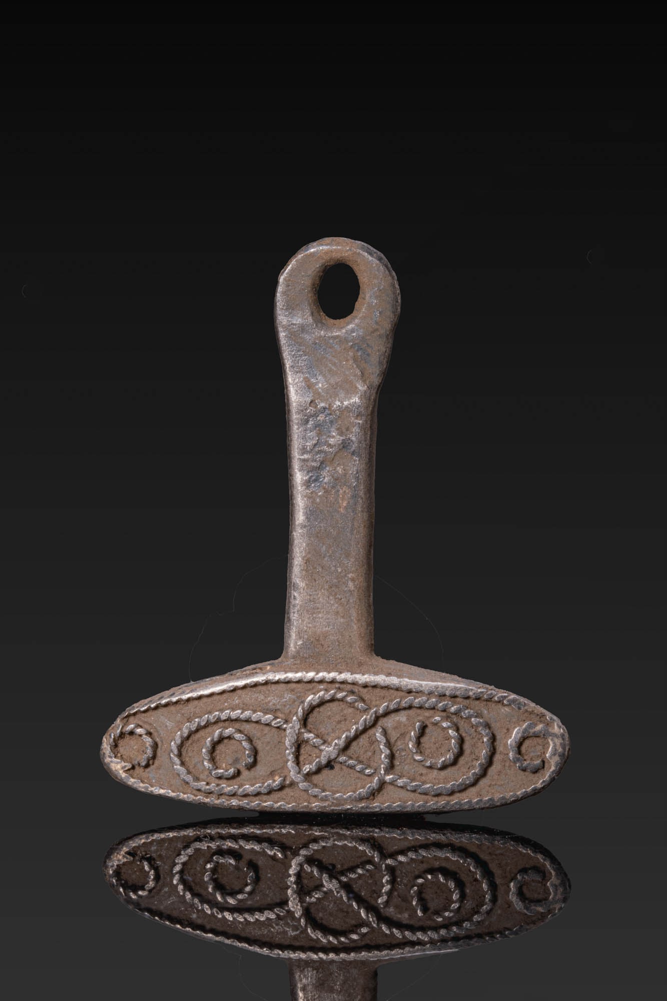 VIKING SILVER MJOLNIR AMULET: Ca. AD 700 - 1000. A silver Mjolnir amulet with a pierced shaft and an elongated head, one face decorated with applied twisted wire in a central interlace motif within a ropework border. The reverse i