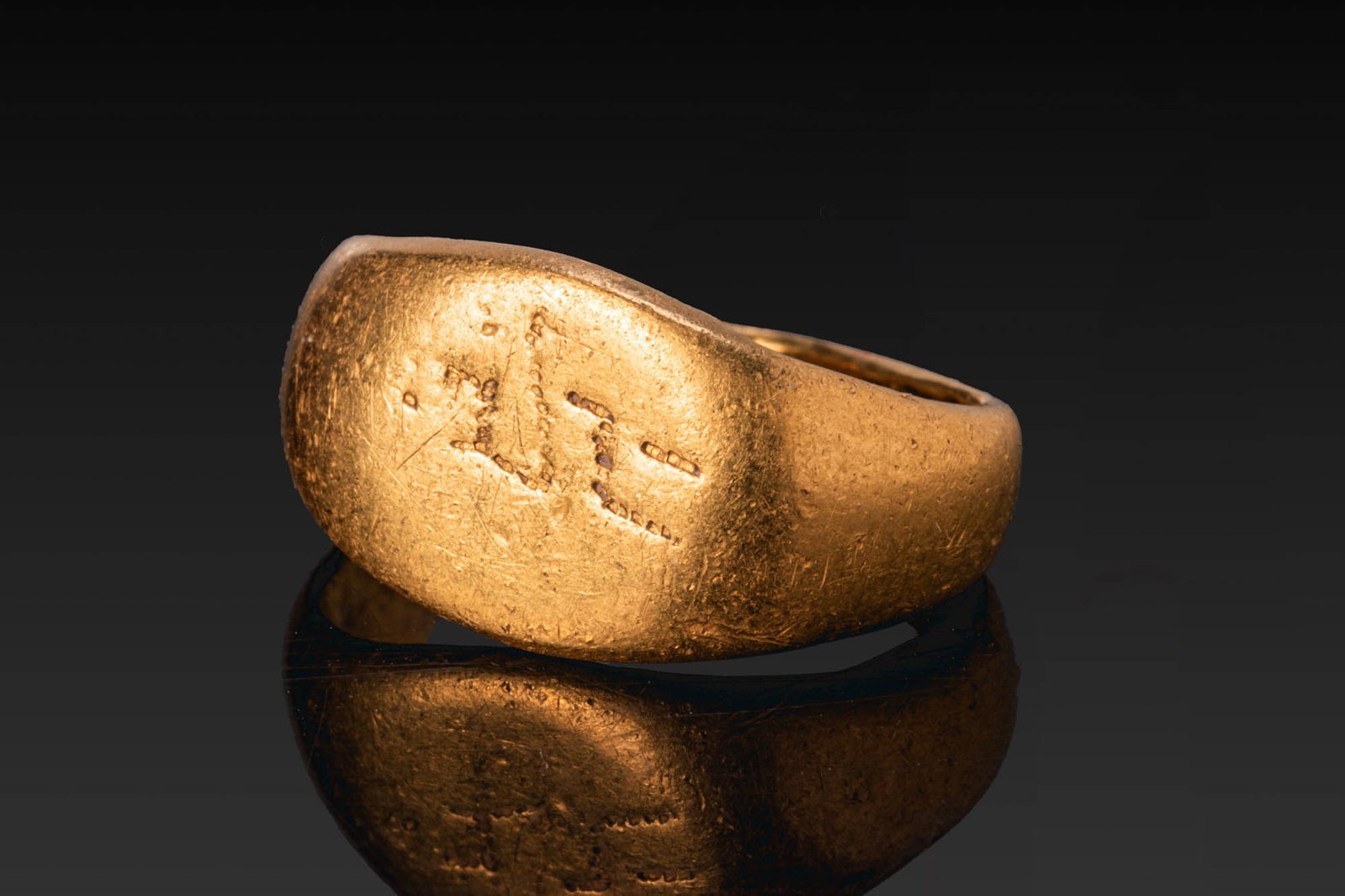 ARAMAIC GOLD RING WITH INSCRIPTION: Ca. AD 1 - 300. A gold ring with a broad, rounded bezel and a plain tapering hoop. The bezel is engraved with a short inscription. For similar see: The British Museum, Museum number 1917,0501.916. Siz