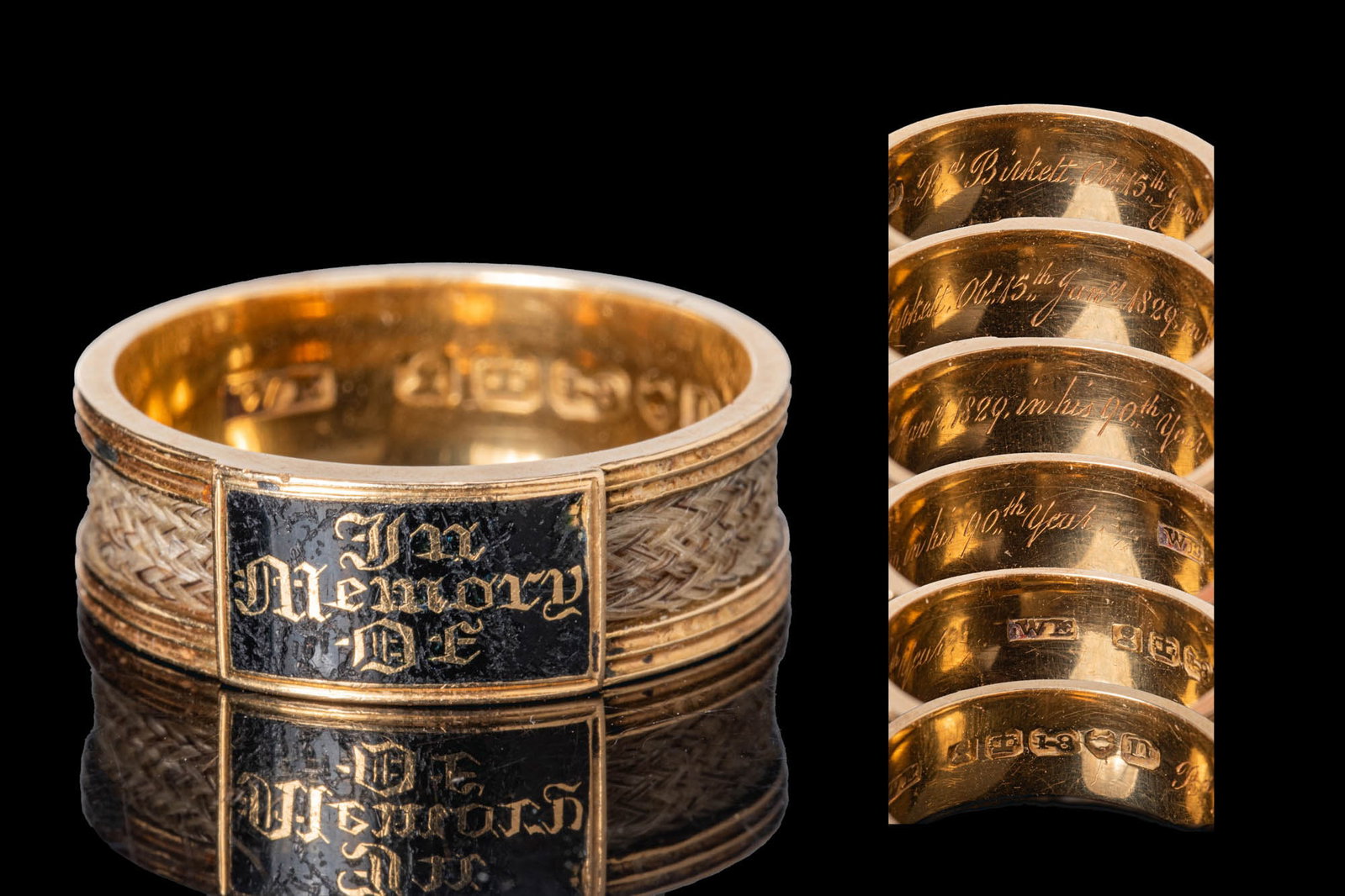 GEORGIAN GOLD MOURNING BAND RING WITH HAIRWORK AND BLACK ENAMEL: Ca. AD 1829. A gold mourning band ring with a compartment of hairwork enclosed within the band, and a rectangular black enamel plaque inscribed in gilt "IN MEMORY OF". The interior is inscribed in cur