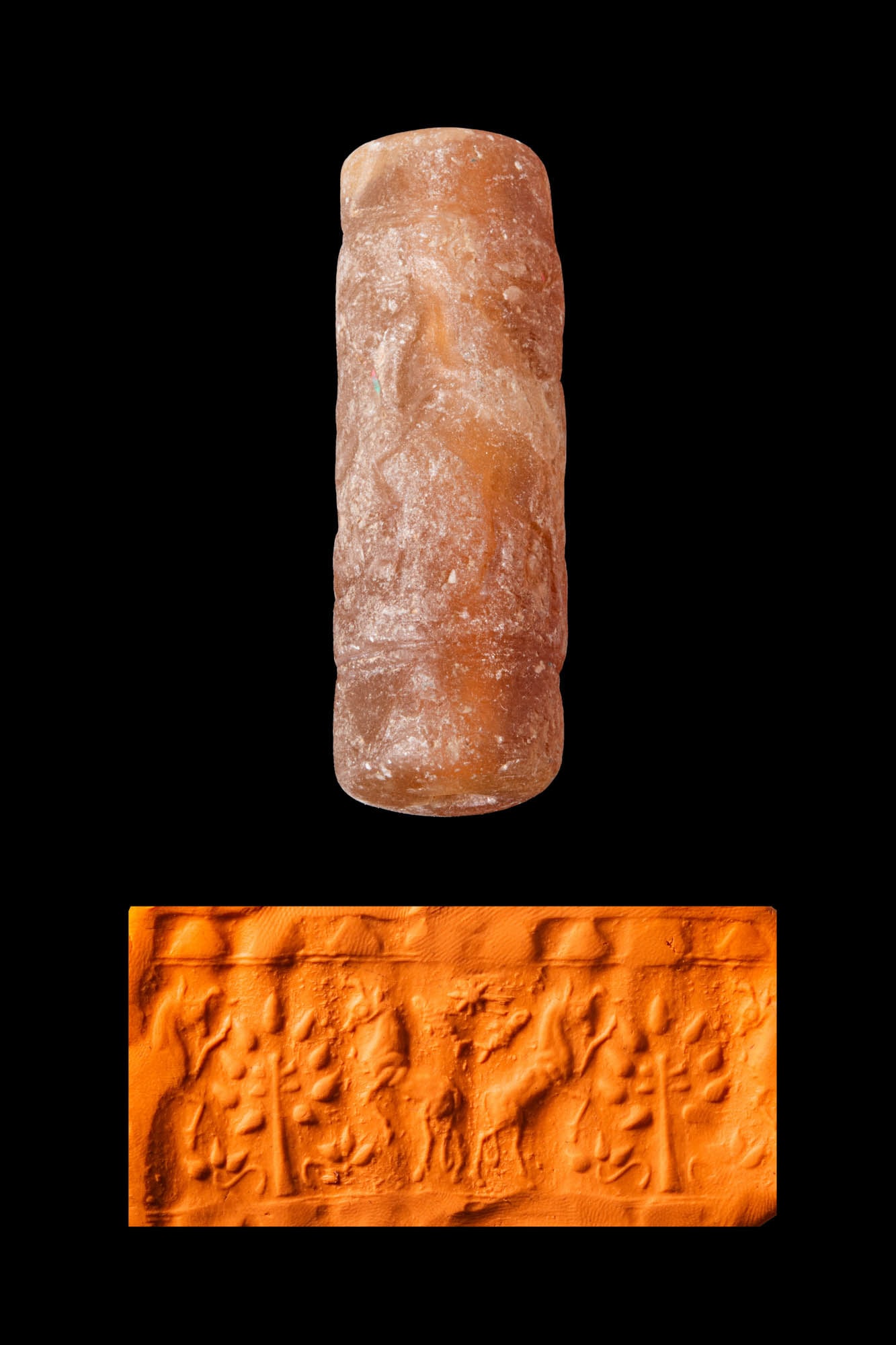 LATE MIDDLE ASSYRIAN OR KASSITE TRANSLUCENT ORANGE STONE CYLINDER SEAL WITH IBEXES AND A TREE: Ca. 1300 - 1000 BC. A translucent orange stone cylinder seal, drilled longitudinally and engraved with a tree flanked by ibexes, with a fish and an eight-pointed star in the exergue. Size: 51mm x 17mm