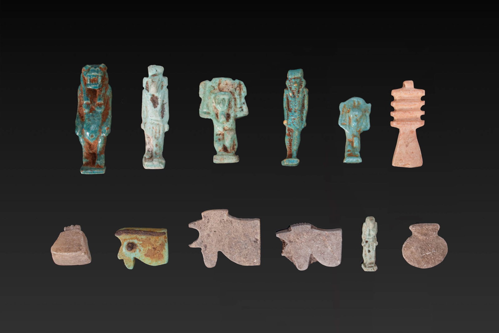 LARGE COLLECTION OF EGYPTIAN FAIENCE AND STONE AMULETS: New Kingdom to Ptolemaic Period, Ca. 1550 - 30 BC. A collection of 12 faience and stone amulets, including, from left to right: a crocodile-headed Taweret; a standing Thoth with ibis head; a kneeling 