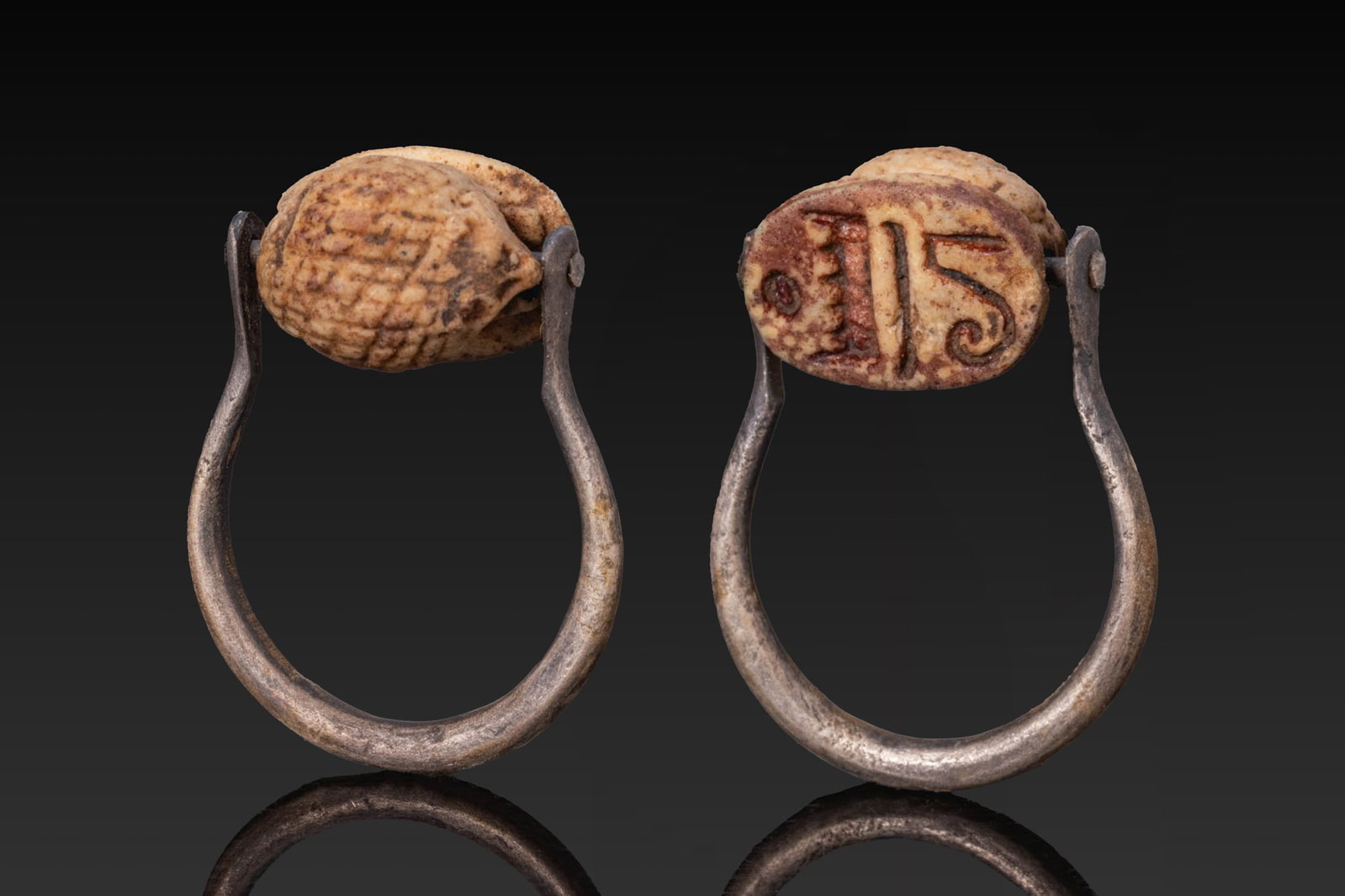 EGYPTIAN STEATITE HEDGEHOG WITH EPITHET OF THUTMOSE III IN SILVER SWIVEL RING: New Kingdom, Ca. 1550 - 1069 BC. A steatite stylised hedgehog. The flat base is inscribed with the epithet of the pharaoh Thutmose III "Image of Amun-Ra". Set in a possibly later silver swivel ring wi