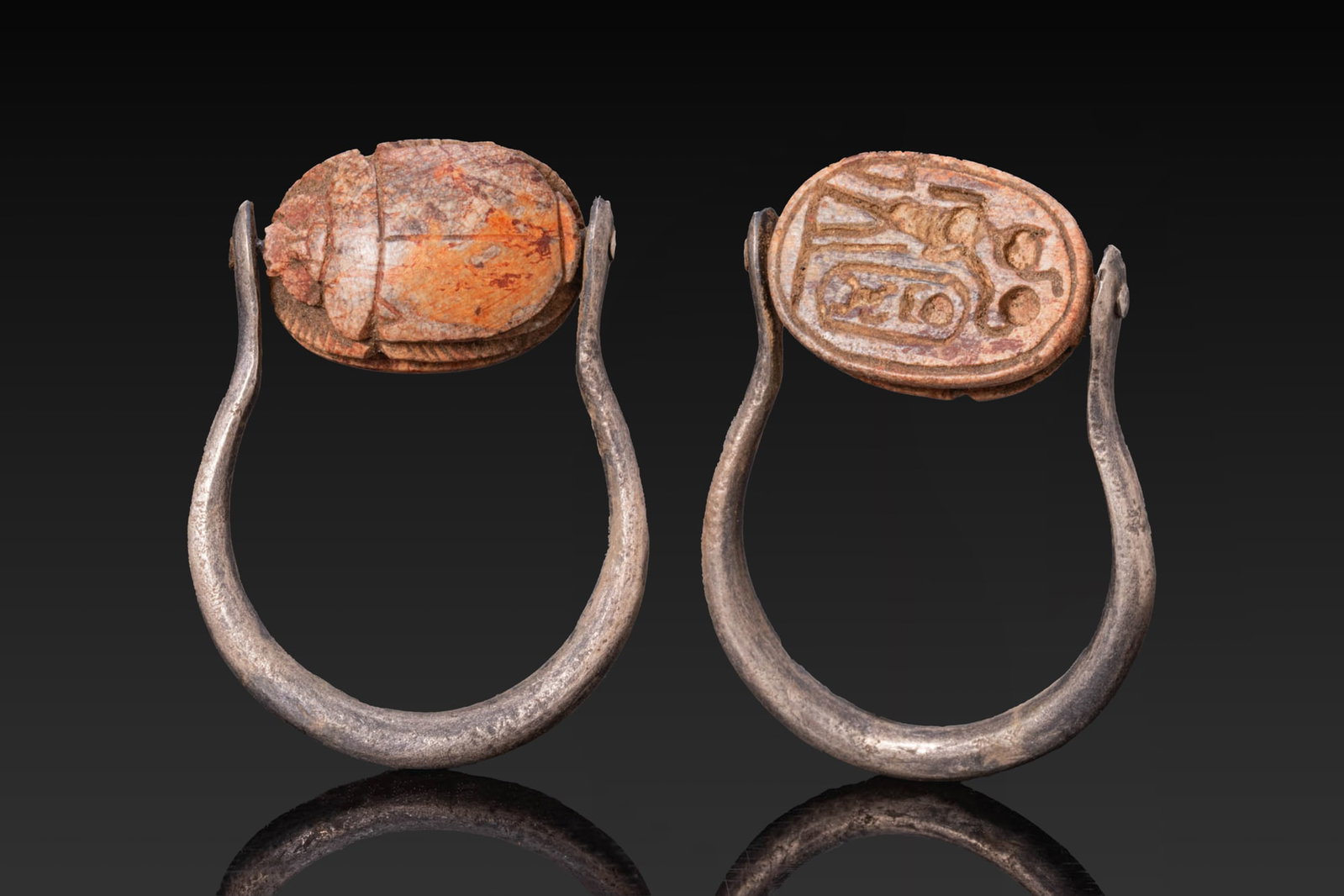 EGYPTIAN (or later) STEATITE SCARAB WITH CARTOUCHE OF THUTMOSE III IN SILVER SWIVEL RING: New Kingdom, Ca. 1550 - 1069 BC (or later). A steatite scarab with a domed back, a single line marking the suture and pronotum, and v-marks at the upper outer edges of the elytra. The legs are incised