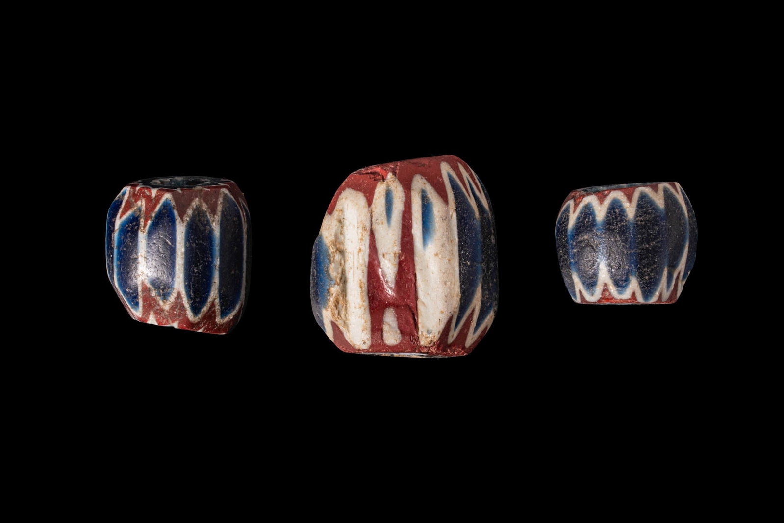 COLLECTION OF LARGE VENETIAN CHEVRON GLASS BEADS: Ca. AD 1500 - 1600. A collection of three glass beads, each of rounded cylindrical form with a central perforation, composed of superimposed layers of dark blue, white, and red glass. For similar see: