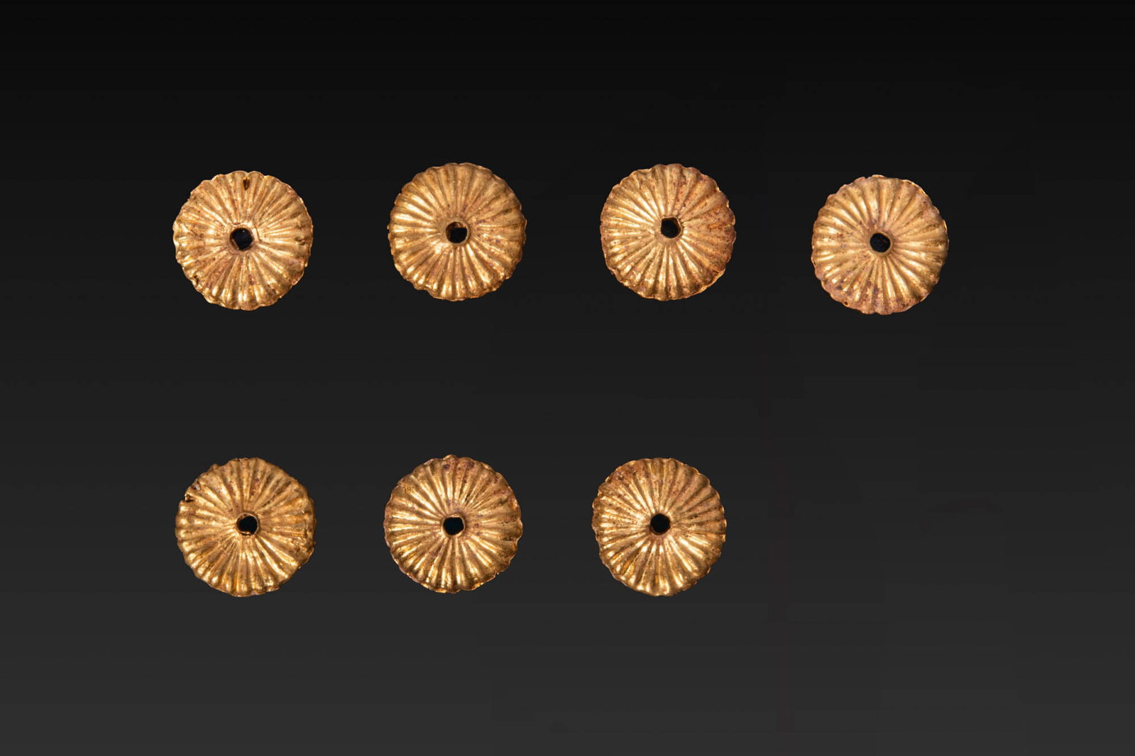 COLLECTION OF GREEK GOLD APPLIQUES: Ca. 700 - 500 BC. A collection of seven gold appliques, each formed as a circular fluted disc with a central perforation. For similar see: E. Formigli, L. A. Scatozza Horicht, Le prime lavorazioni del
