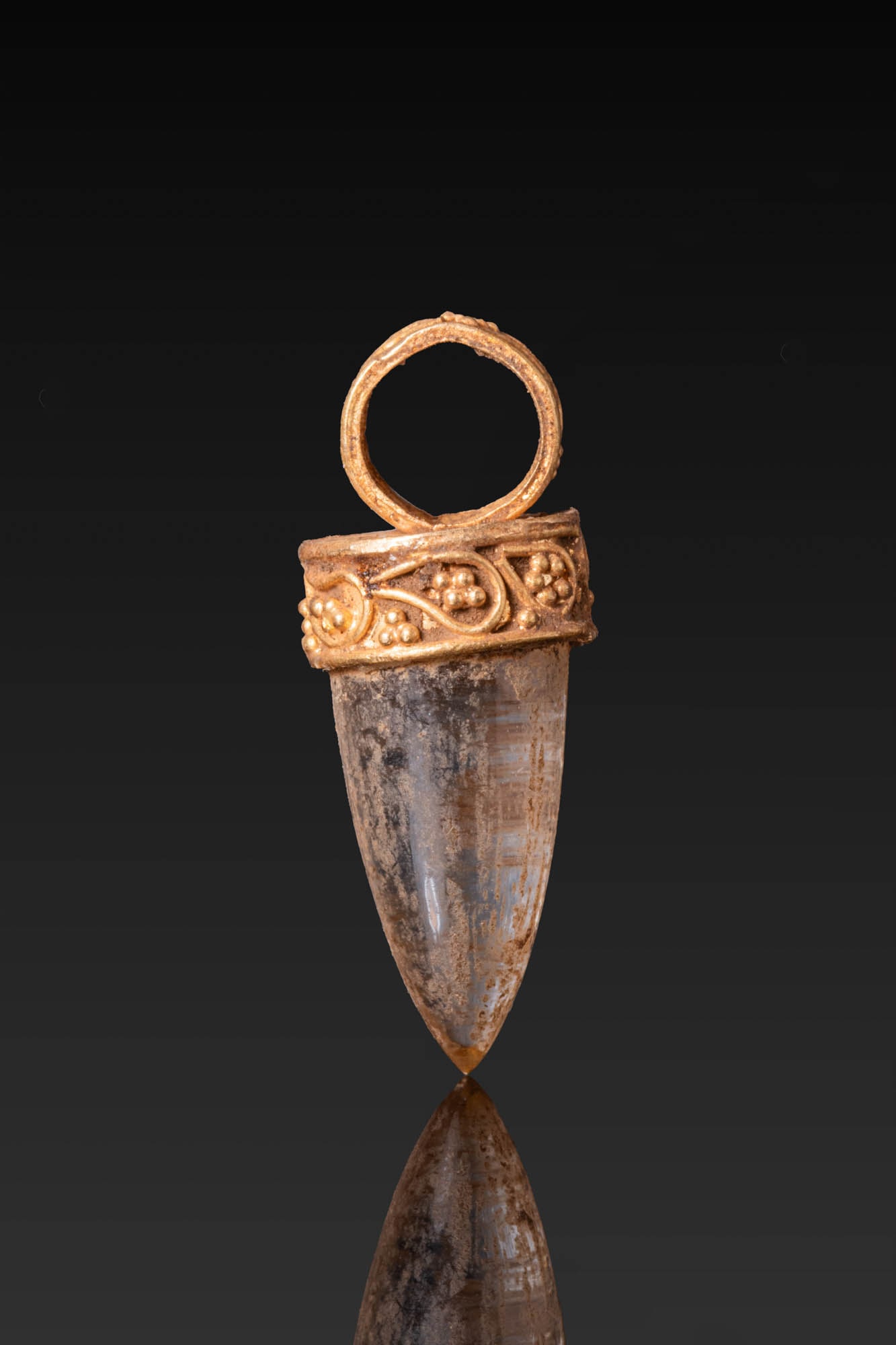 HELLENISTIC HIGH KARAT GOLD PENDANT WITH ROCK CRYSTAL: Ca. 300 - 100 BC. A gold pendant set with a tapered rock crystal drop in a circular mount with a plain upper plate, the collar and suspension loop decorated with granulation and drop-shaped motifs in 