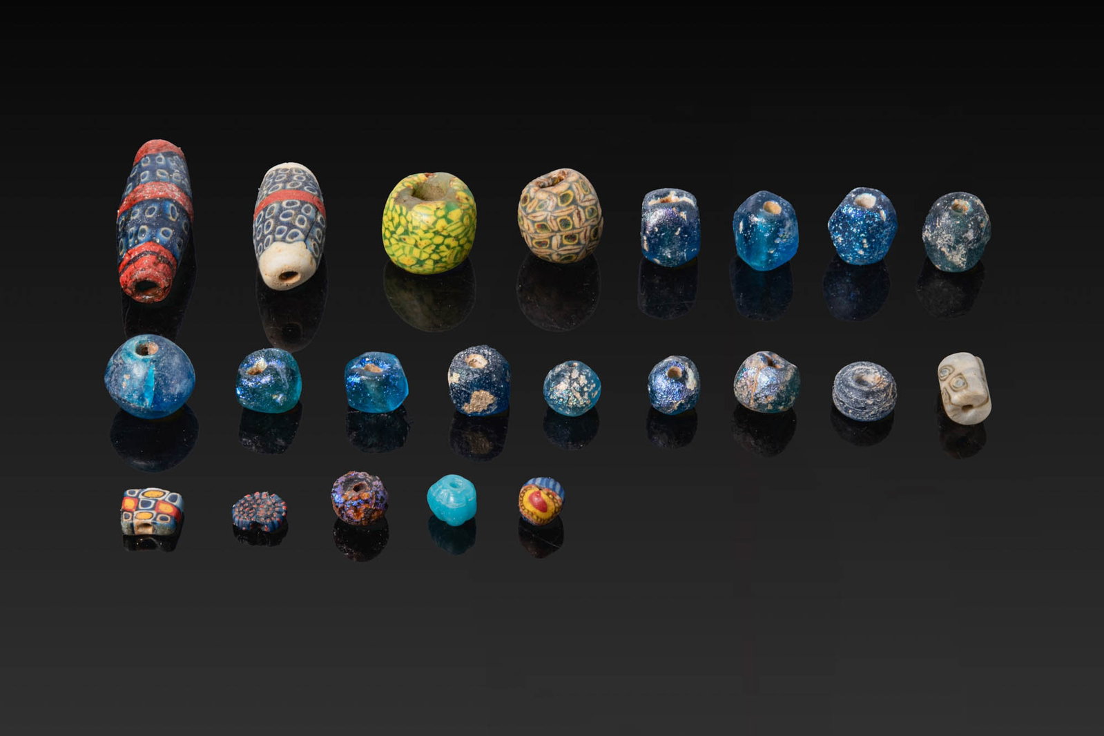 COLLECTION OF GREEK AND ROMAN GLASS BEADS: Ca. 500 BC - AD 200. A collection of 22 glass beads, including rounded, square, and tubular examples with mosaic decoration, together with plain blue beads. For similar see: The Metropolitan Museum of