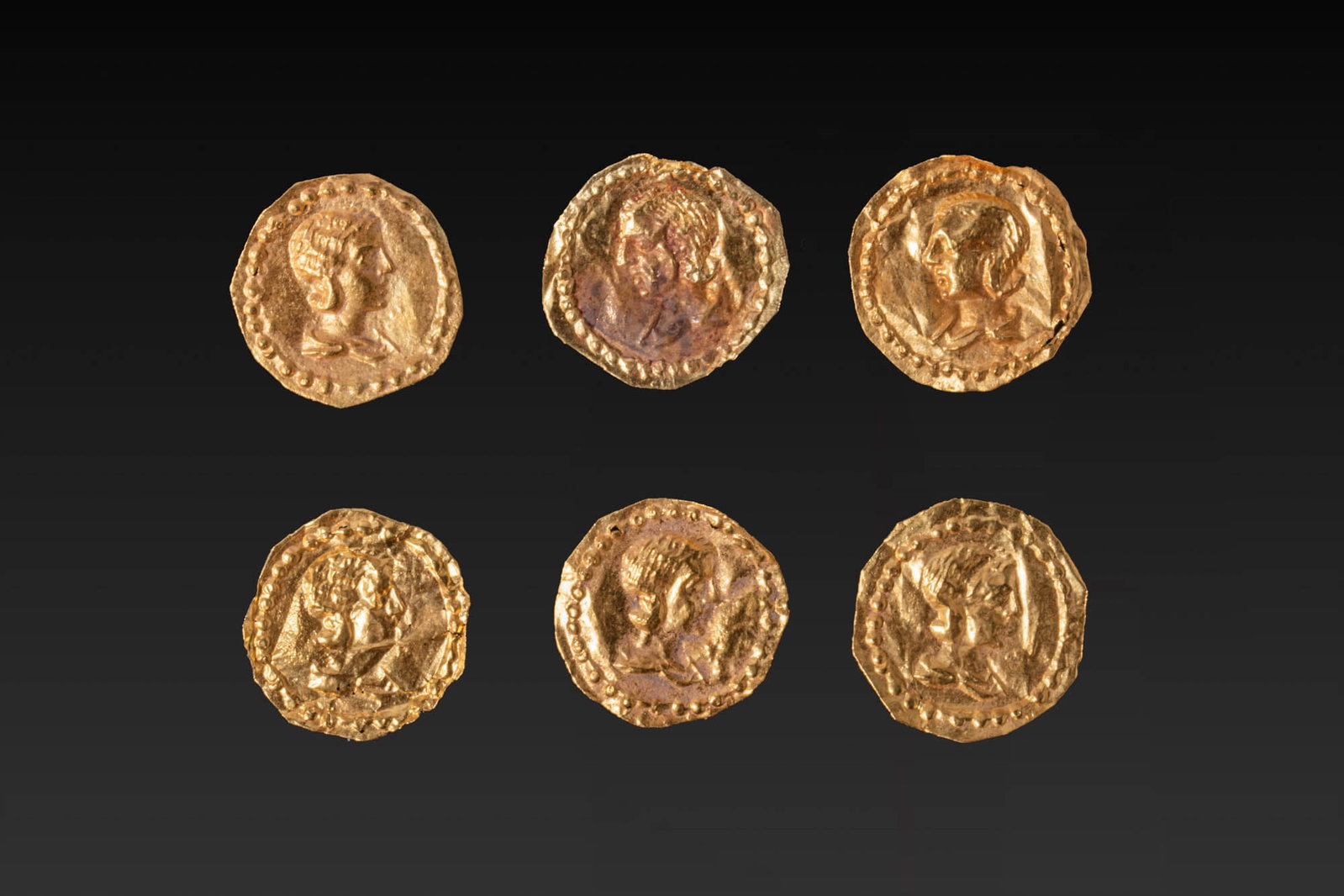 COLLECTION OF ROMAN GOLD APPLIQUES WITH FEMALE PORTRAITS: Ca. AD 200 - 300. A collection of six gold circular appliques, each with an irregular outer edge and a border of punched dots, decorated in repousse with the profile bust of a female figure. Size: 13-