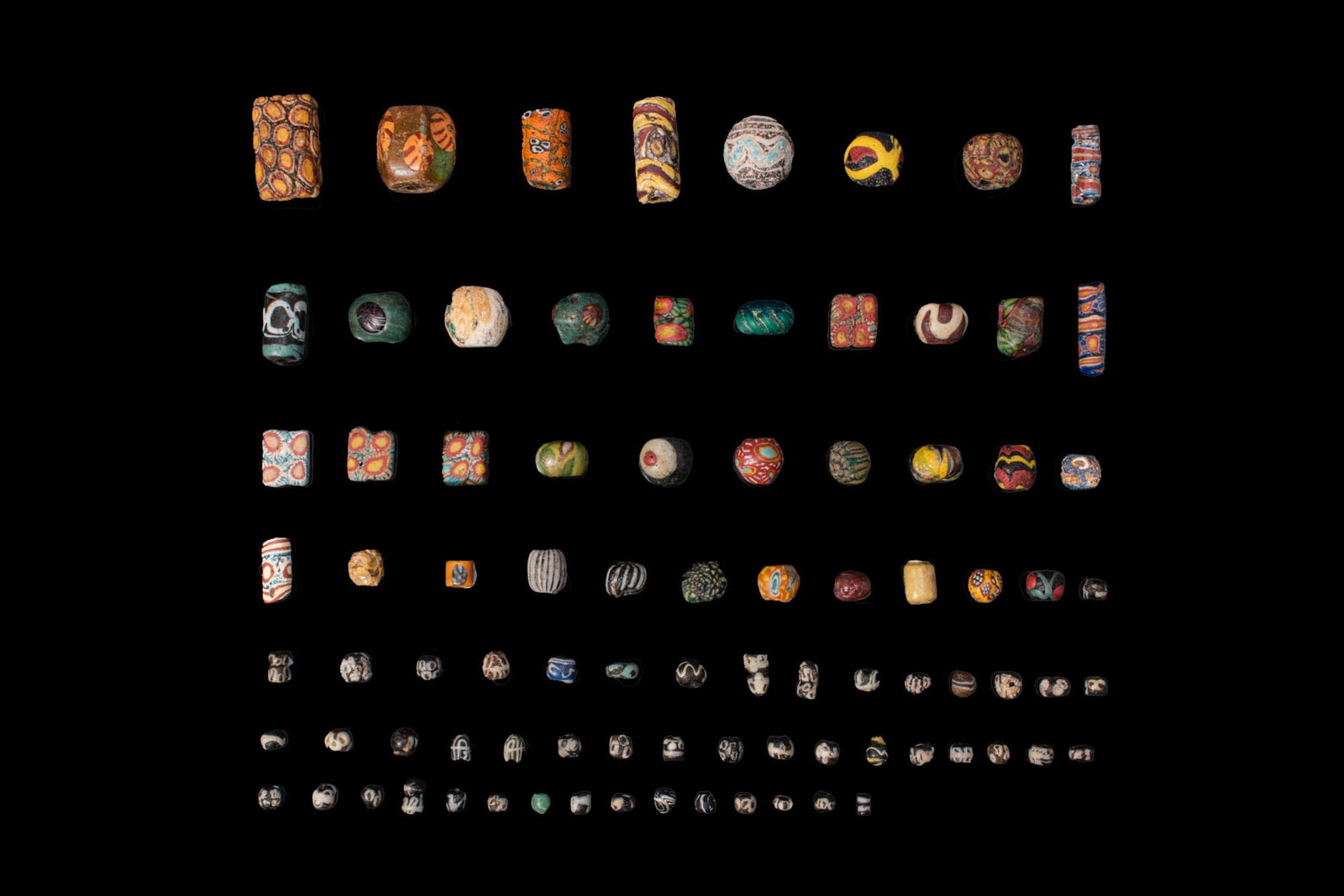 LARGE COLLECTION OF GREEK AND ROMAN GLASS BEADS: Ca. 300 BC - AD 200. A collection of 87 opaque and translucent glass beads, including spherical, biconical, cylindrical and flat examples, decorated with vivid polychrome canes, concentric eye motifs,