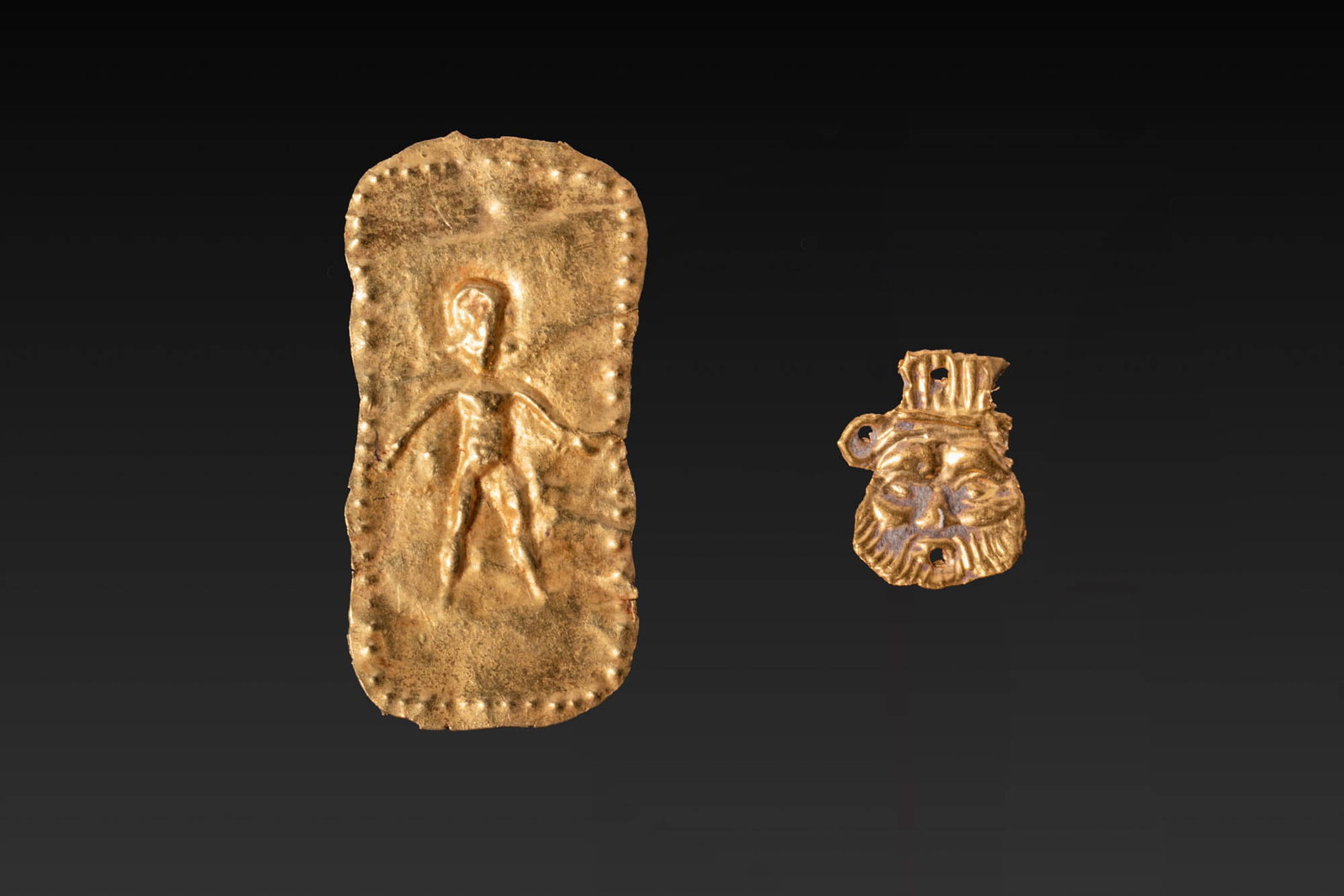 PAIR OF PHOENICIAN GOLD APPLIQUES: Ca. 800 - 300 BC. A pair of gold appliques, including, from left to right: a rectangular thin sheet applique with rounded ends, decorated in repousse with a simplified standing figure framed by a bord