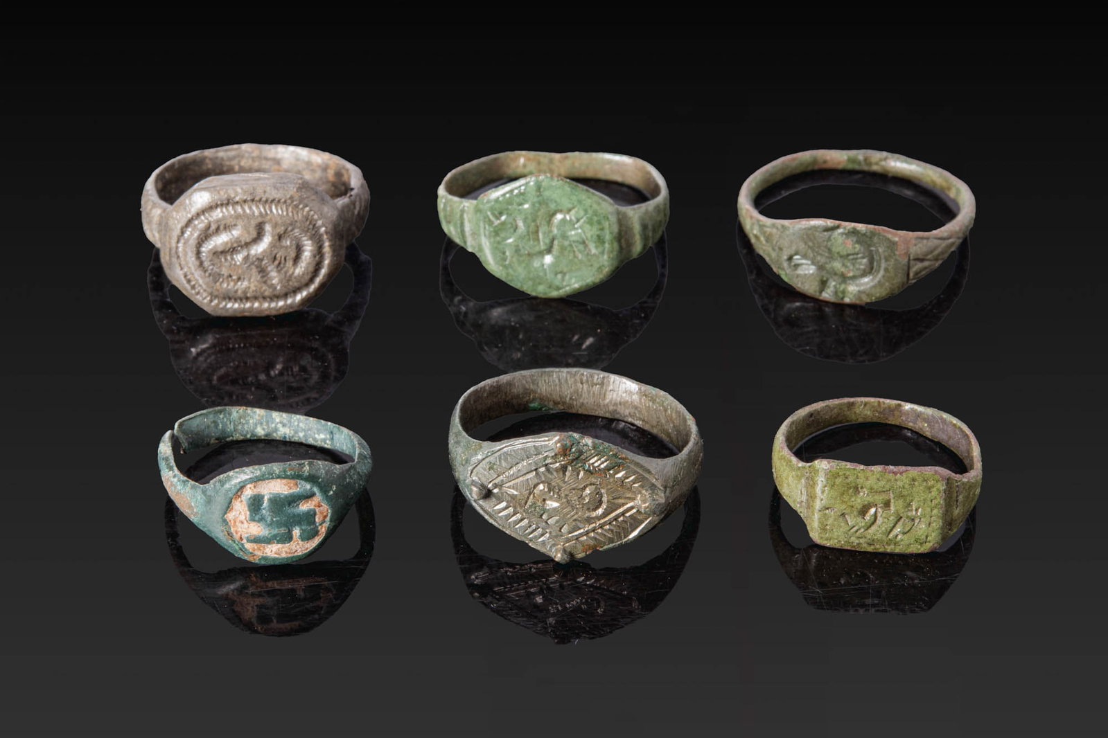 COLLECTION OF LATE ROMAN AND VIKING BRONZE AND SILVER RINGS: Ca. AD 400 - 800. A collection of six bronze and silver rings, including, from top left: a ring with a broad oval bezel engraved with curvilinear motifs; a ring with a hexagonal bezel engraved with a 