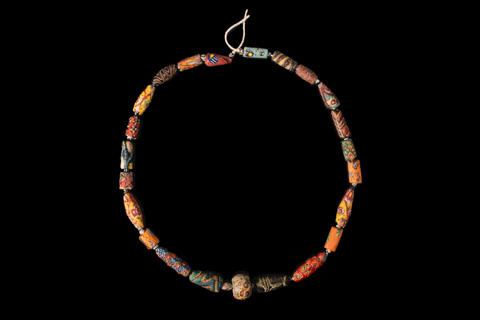 ROMAN MOSAIC GLASS BEAD NECKLACE: Ca. 100 BC - AD 200. A necklace strand composed of cylindrical and barrel-shaped mosaic glass beads, decorated with polychrome canes in red, yellow, blue, green, white, and black, interspersed with sm