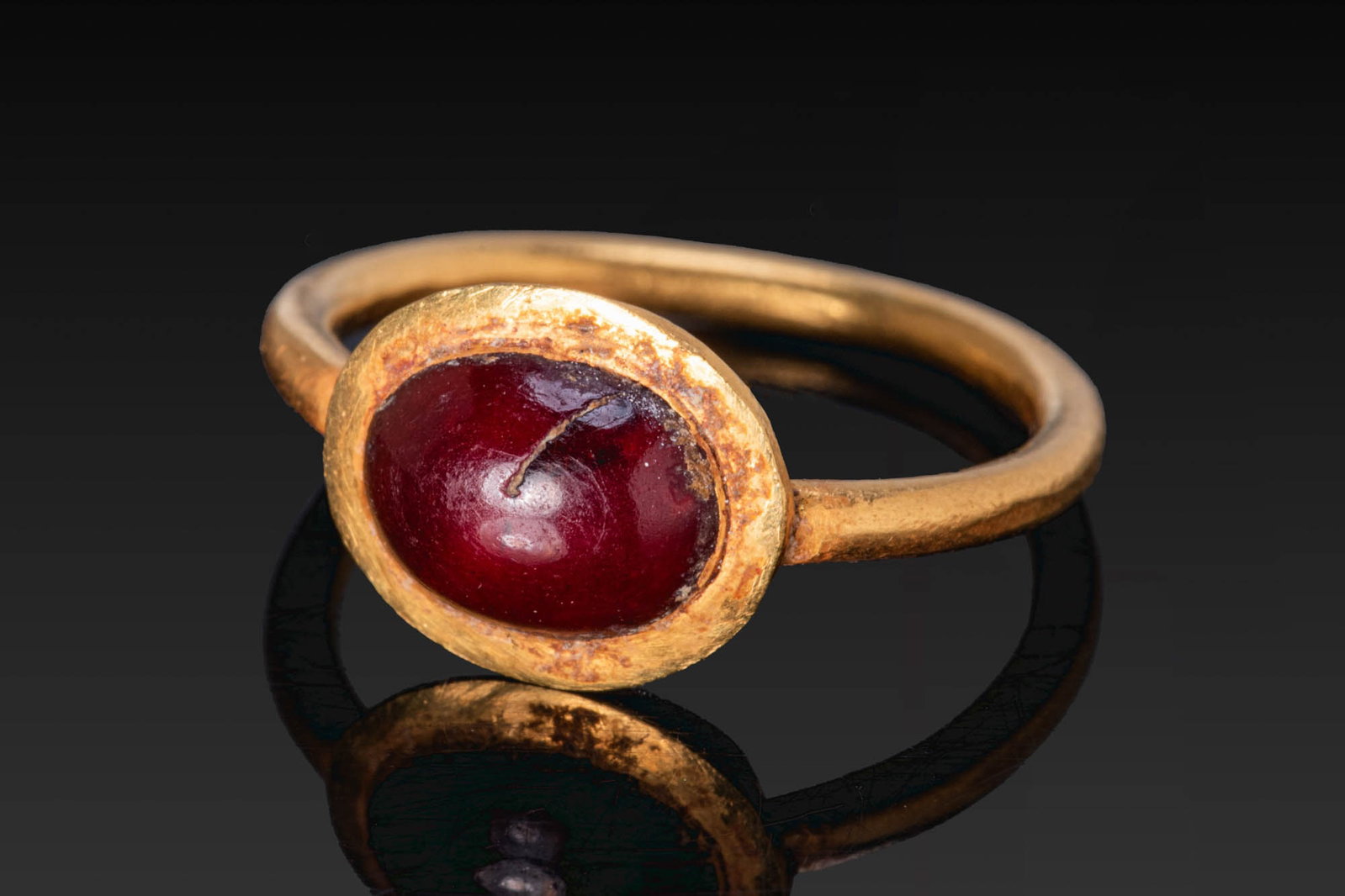 BYZANTINE GOLD RING WITH RED GARNET CABOCHON: Ca. AD 400 - 600. A gold ring with a slender, round-section hoop and an oval bezel set with a red garnet cabochon. Size: D:12mm / US: 44928 / UK: A; Weight: 1.3g Provenance: Private London collection;