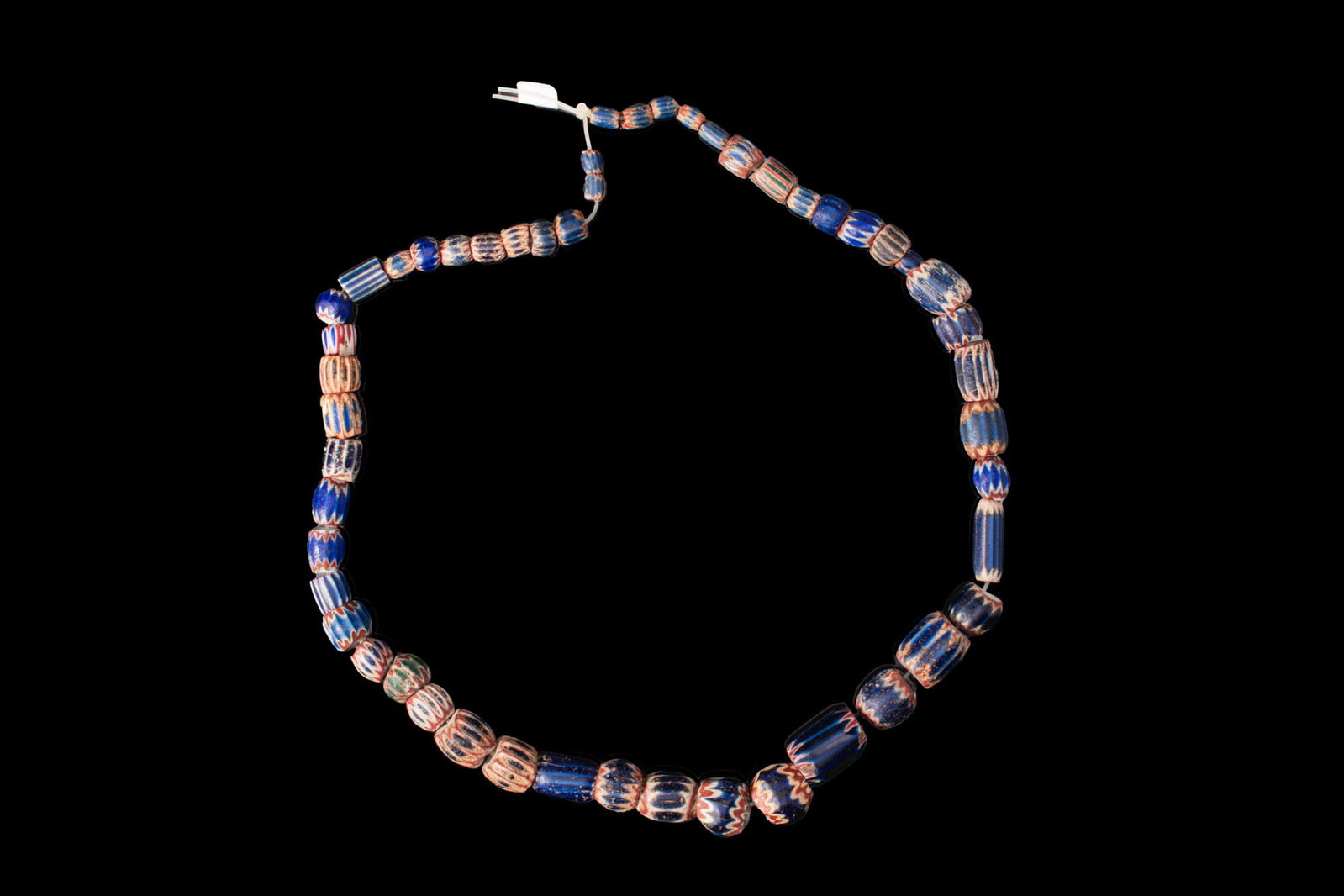 VENETIAN CHEVRON GLASS BEAD NECKLACE: Ca. AD 1500 - 1600. A necklace strand composed of chevron glass beads of barrel-shaped, cylindrical, and rounded forms, in blue glass with white and red. For similar see: The Corning Museum of Glass, 