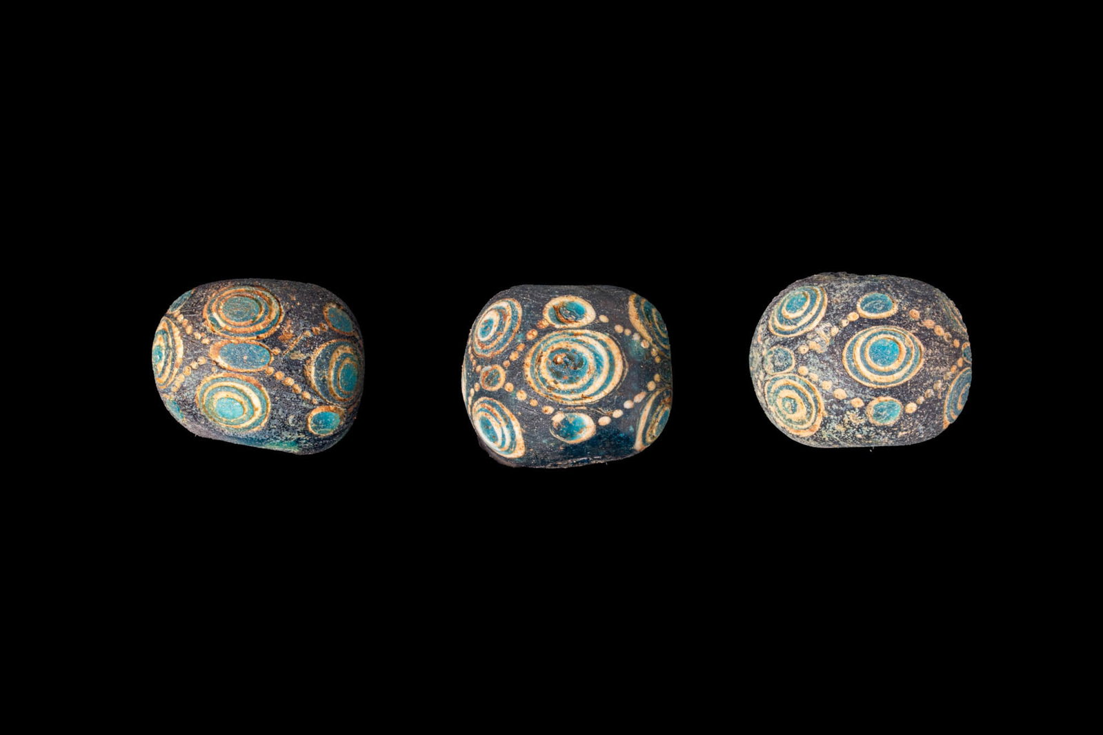 COLLECTION OF LARGE CHINESE POLYCHROME GLASS EYE BEADS: Ca. 770 - 256 BC. A collection of three dragonfly glass eye beads, each with a globular body decorated with concentric trailed eyes linked by short dotted lines. For similar see: The British Museum, M