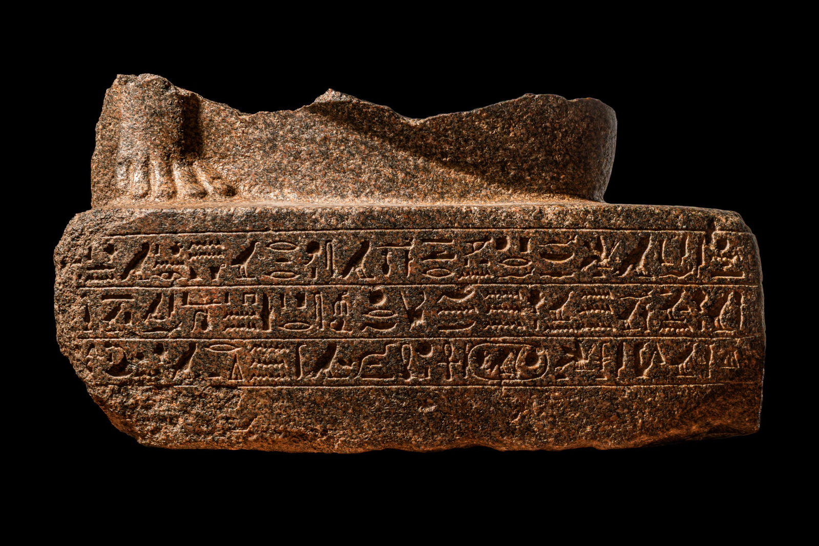 MONUMENTAL EGYPTIAN BASE OF A SCULPTURE BELONGING TO THE MASTER HORIRAA: Second half of Dynasty XXVI, Ca. 664 - 525 BC. A lower fragment of a granite sculpture of a high-ranking person in Egyptian society on a rectangular base. Thanks to the conservation of this lower part