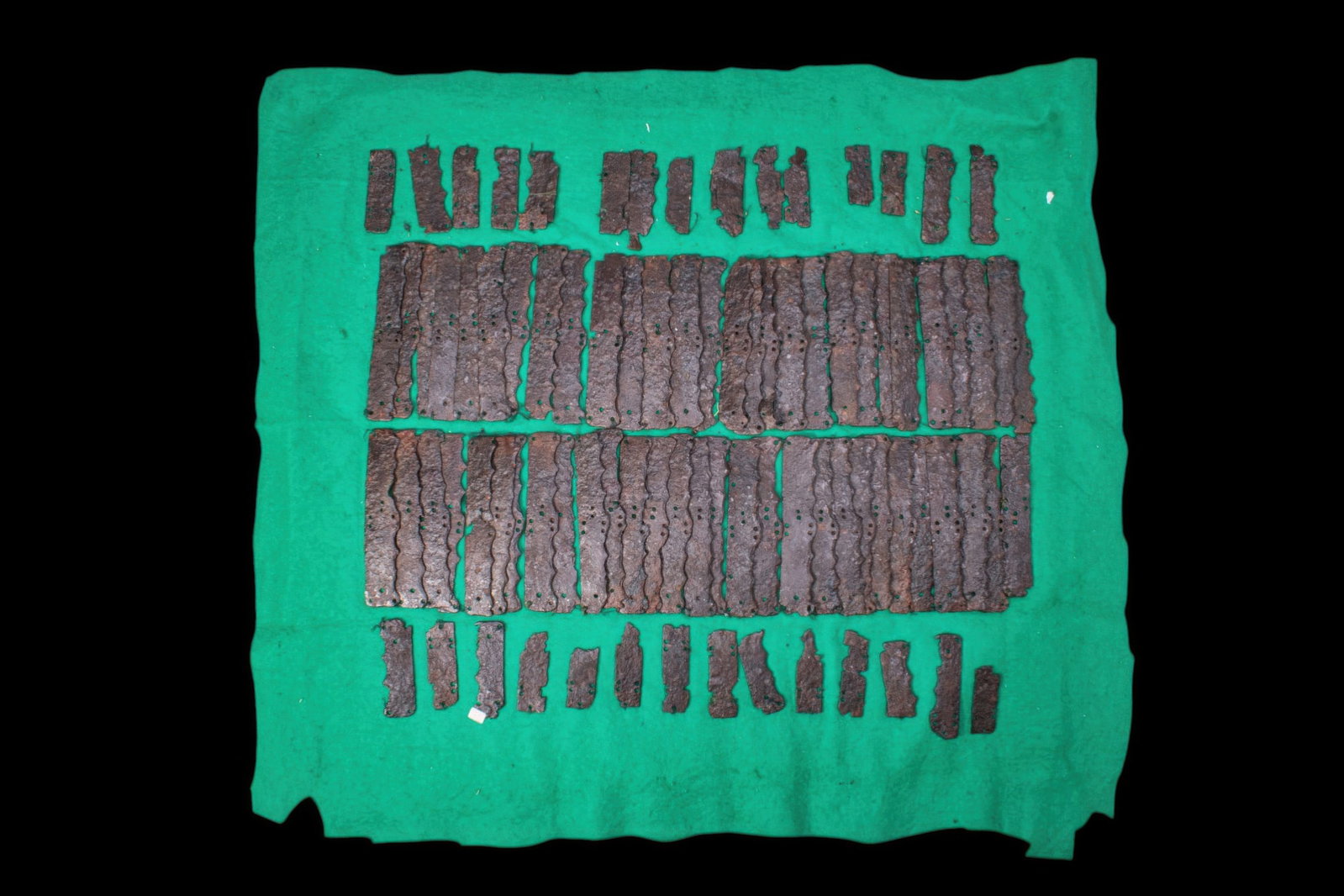 RARE SAXON IRON ARMOUR: Ca. AD 700 - 1000. An iron lamellar armour composed of numerous rectangular plates, each pierced with attachment holes and with a scalloped outer edge. Size: 510mm x 470mm; Weight: 1.37kg Provenance: 