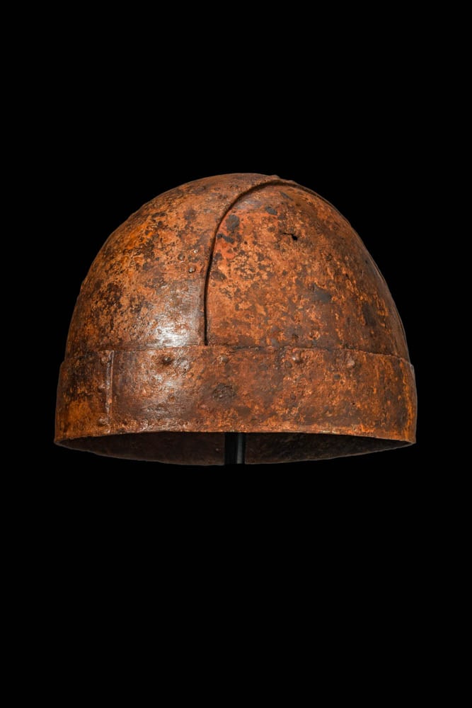 RARE KHAZAR IRON EQUESTRIAN EQUIPMENT: Ca. AD 900 - 1000. An iron equestrian equipment including, from upper left to right: a domed helmet with a broad band running across the crown and a lower riveted band encircling the base; a pair of s