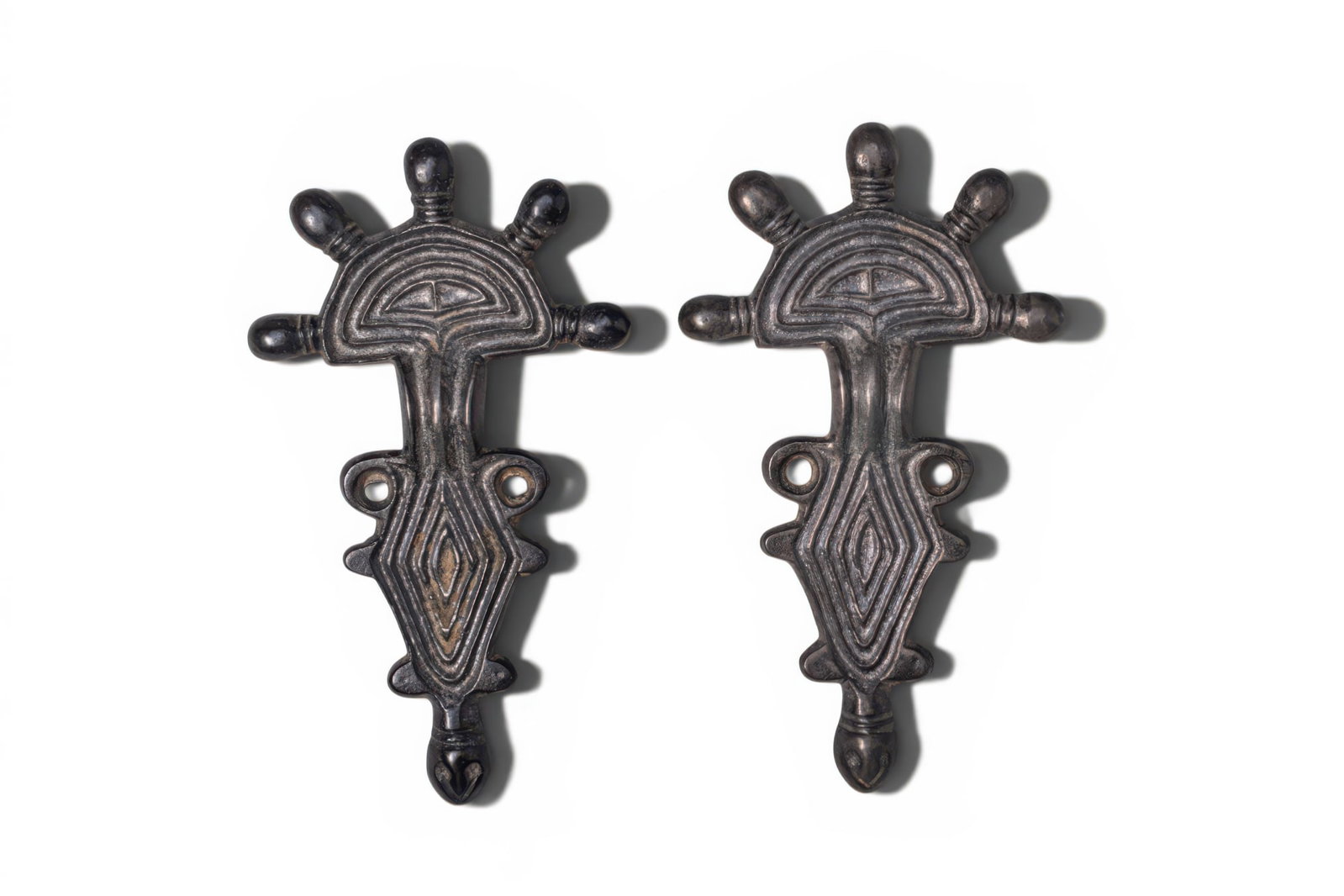 PAIR OF OSTROGOTHIC SILVER ALLOY FIBULAS: Ca. AD 500 - 600. A pair of silver fibulas, each composed of a half-round head plate surmounted by five knop terminals, above a short ribbed arched bow and a lozenge-shaped foot. The foot is flanked b