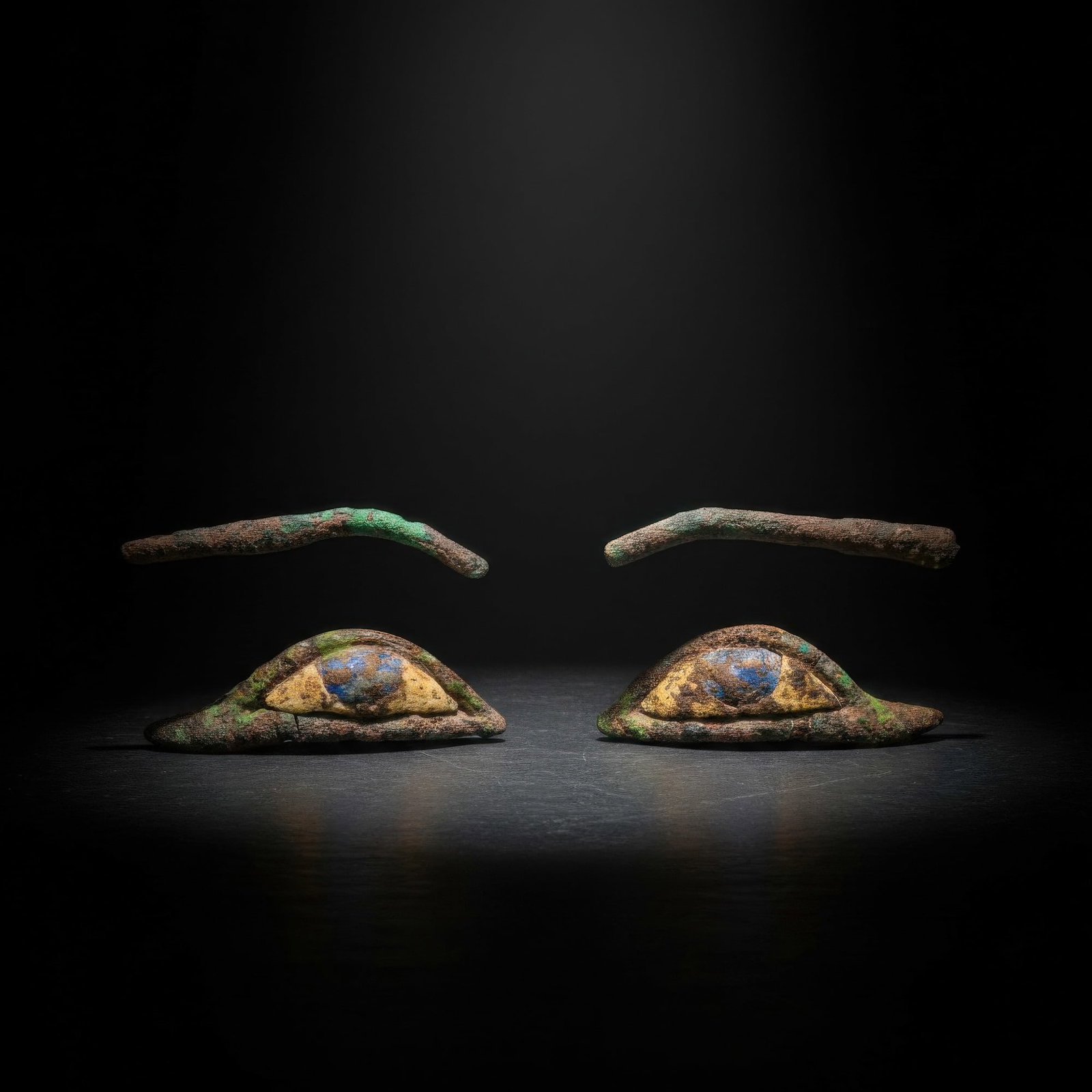 PAIR OF EGYPTIAN BRONZE EYES AND BROWS: Late Period, Ca. 664 - 332 BC. A matching set of mummy inlays comprising a pair of eyes and brows. Each eye is constructed from a bronze frame with a white stone sclera and a circular blue stone iris.