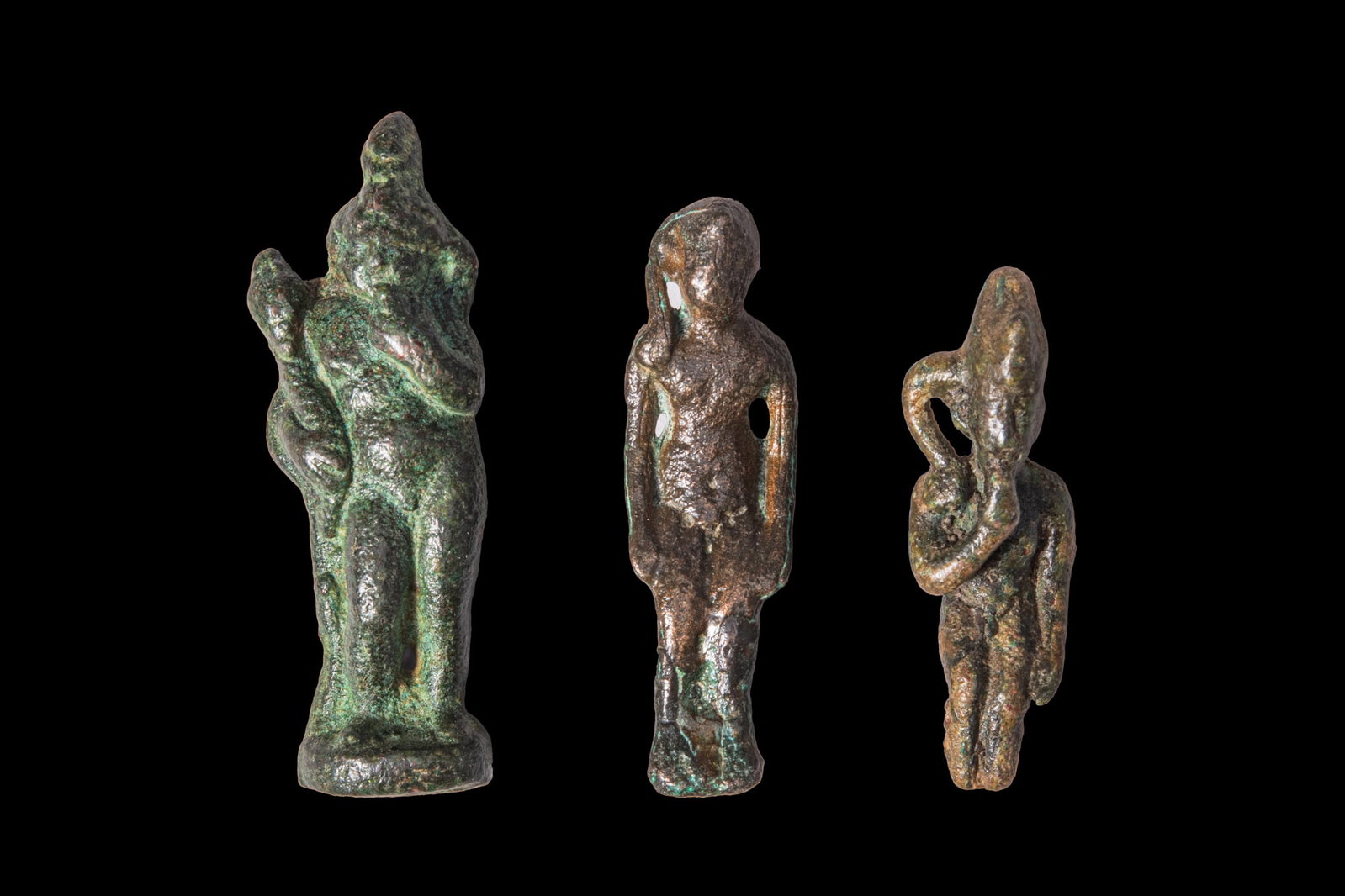 COLLECTION OF EGYPTIAN BRONZE FIGURINES OF HARPOKRATES: Late Period to Ptolemaic Period, Ca. 664 - 30 BC. A collection of three bronze figurines of Harpokrates, including, from left to right: Harpokrates standing nude on a circular base, with one hand rais