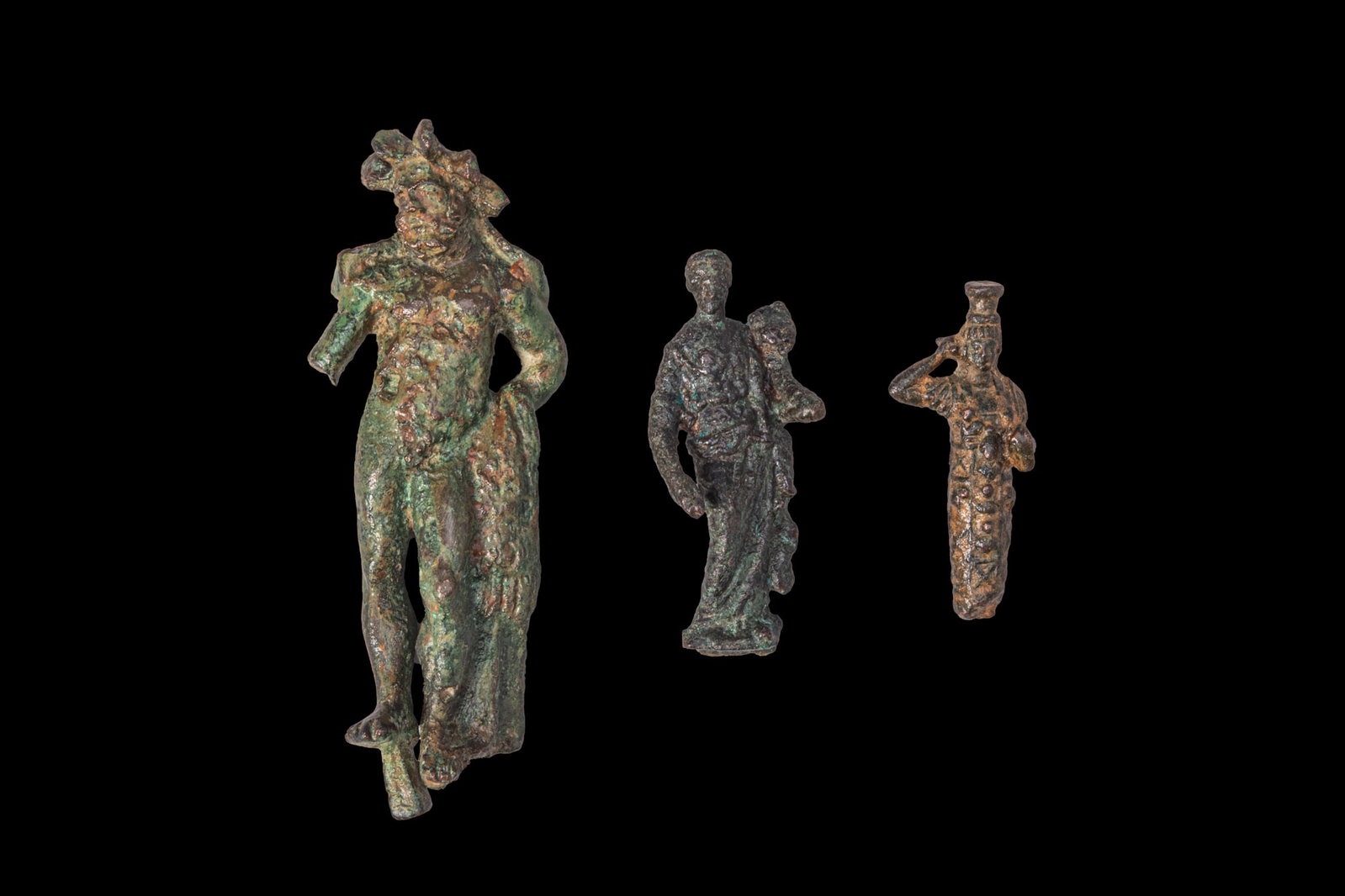 COLLECTION OF ROMAN BRONZE FIGURES OF DEITIES: Ca. AD 1 - 300. A collection of three bronze figures, including, from left to right: Zeus, bearded and standing nude, with a laurel wreath and a mantle over his left arm; Fortuna, draped and standing,