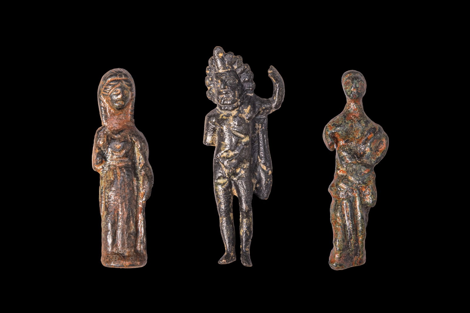 COLLECTION OF ROMAN BRONZE FIGURINES: Ca. AD 1 - 300. A collection of three bronze figurines, including, from left to right: a draped female figure; Zeus, standing nude with a wreath and mantle over his left arm; and a togatus. For simila