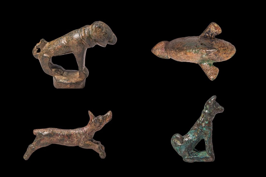 COLLECTION OF ROMAN BRONZE ANIMAL FIGURINES: Ca. AD 100 - 300. A collection of four bronze animal figurines, including, from top to bottom: a dog standing on a circular base, with the head lowered, the body held in a tense forward pose, and the 